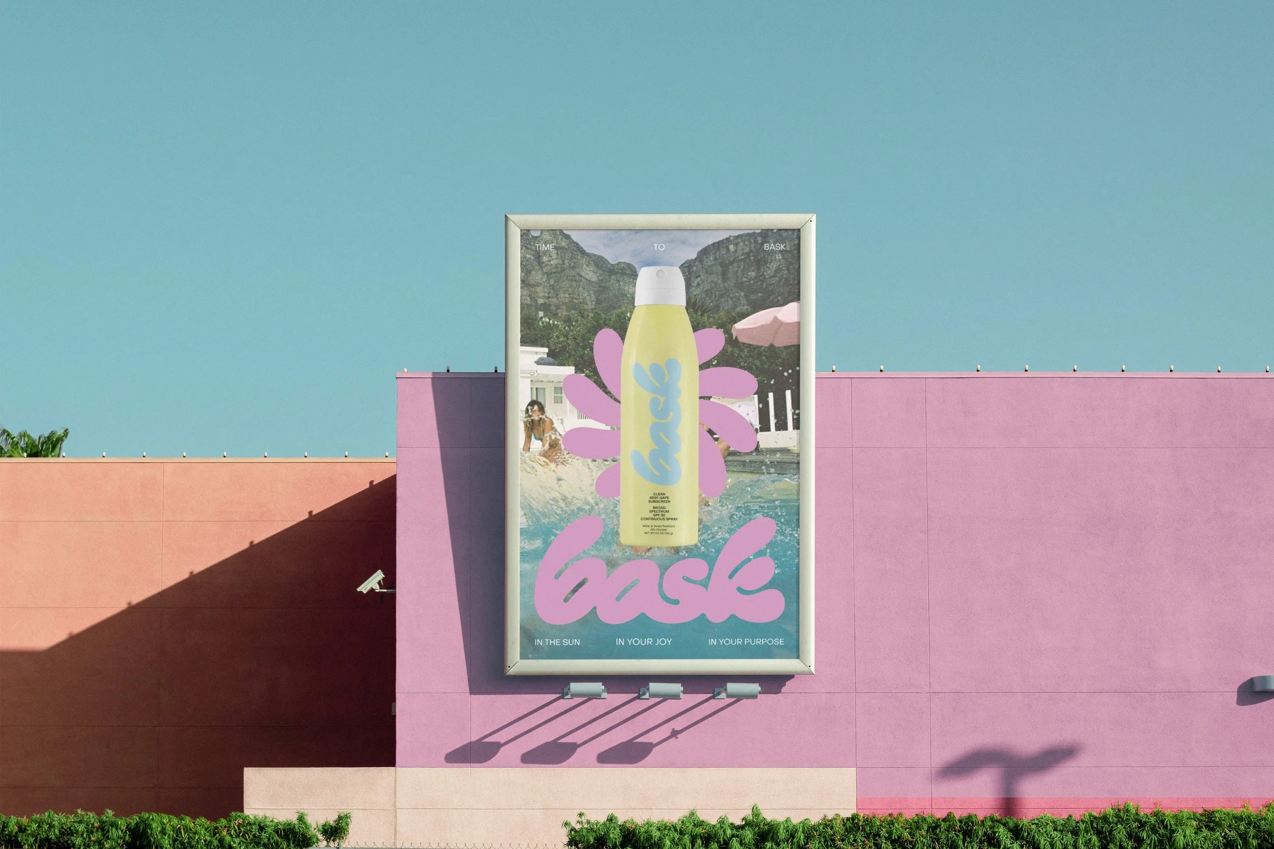Large billboard on a pink building featuring an advertisement for a spray product called 'hairs'. The ad shows a yellow spray bottle surrounded by pink splashes, set against a background of a beach scene with a woman sitting by the pool, mountains, a