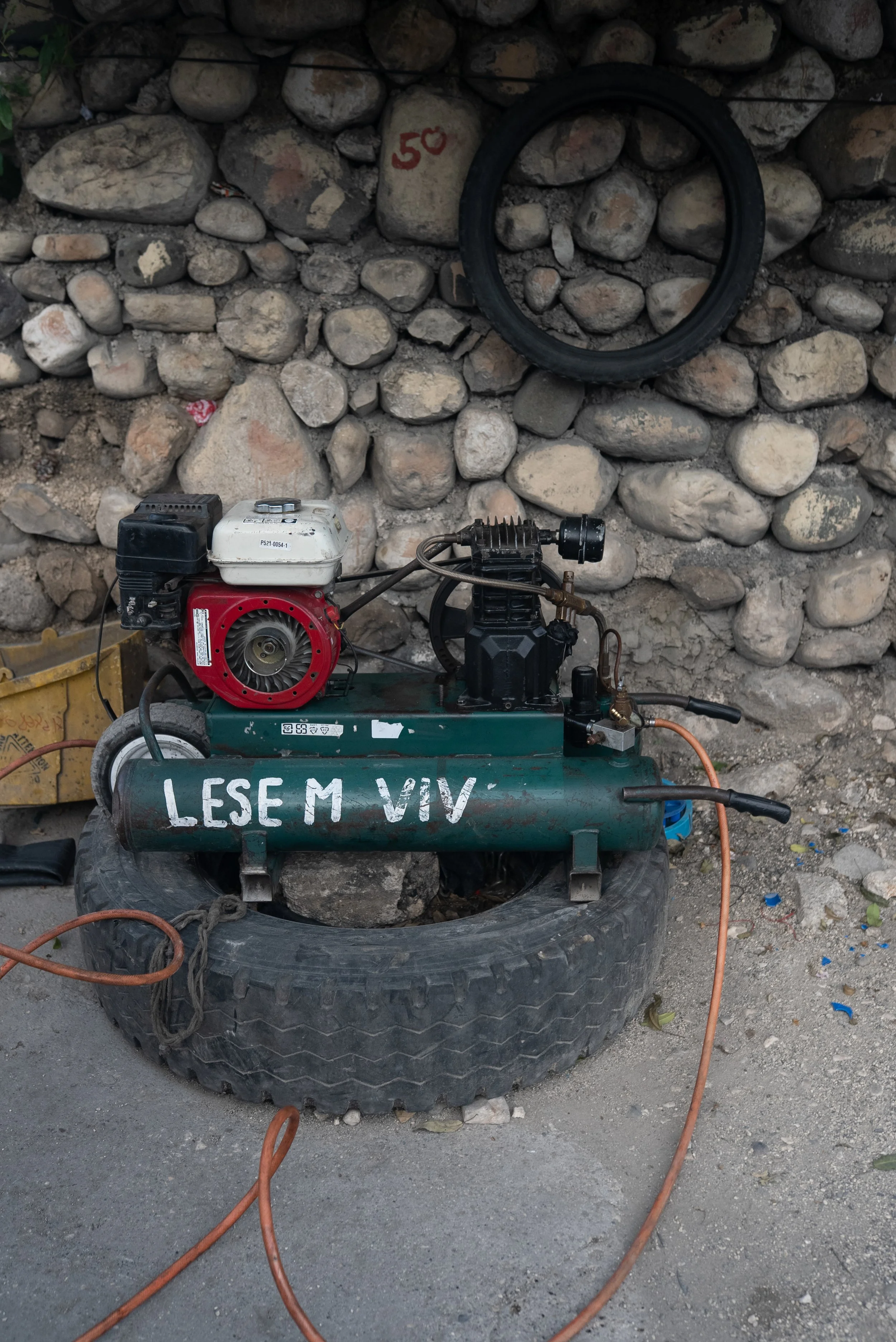 "Let me live" graffitted onto a mechanics workwear for motorcycle taxi drivers in Port-au-Prince.