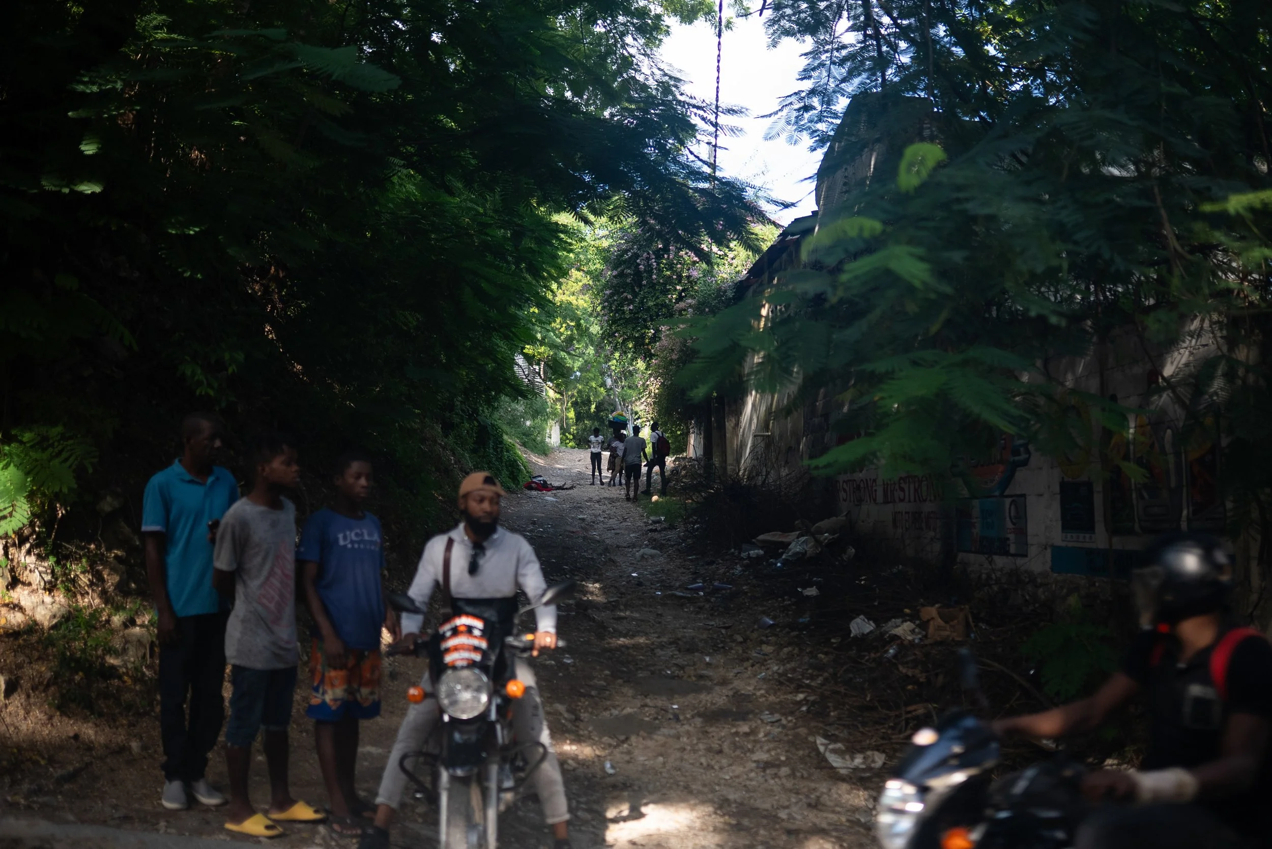 The bodies of to deceased victims of armed groups discarded in an alley as motorcycle taxi drivers continue work in Port-au-Prince.