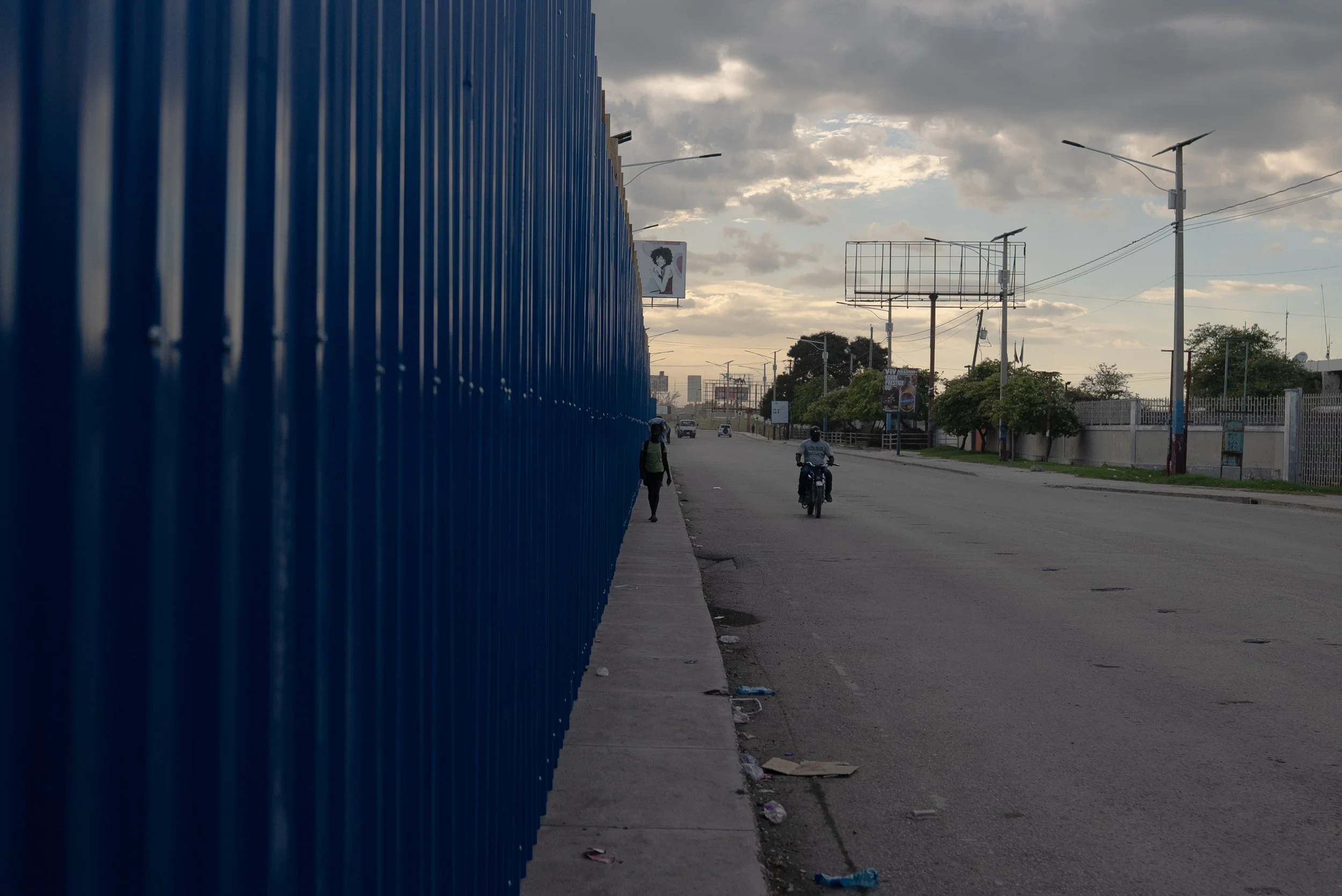 Motorcycle taxi drivers drive past the boarded up Hugo Chavez Plaza where many displaced people took shelter after armed groups forced them out of their neighborhoods in Port-au-Prince.