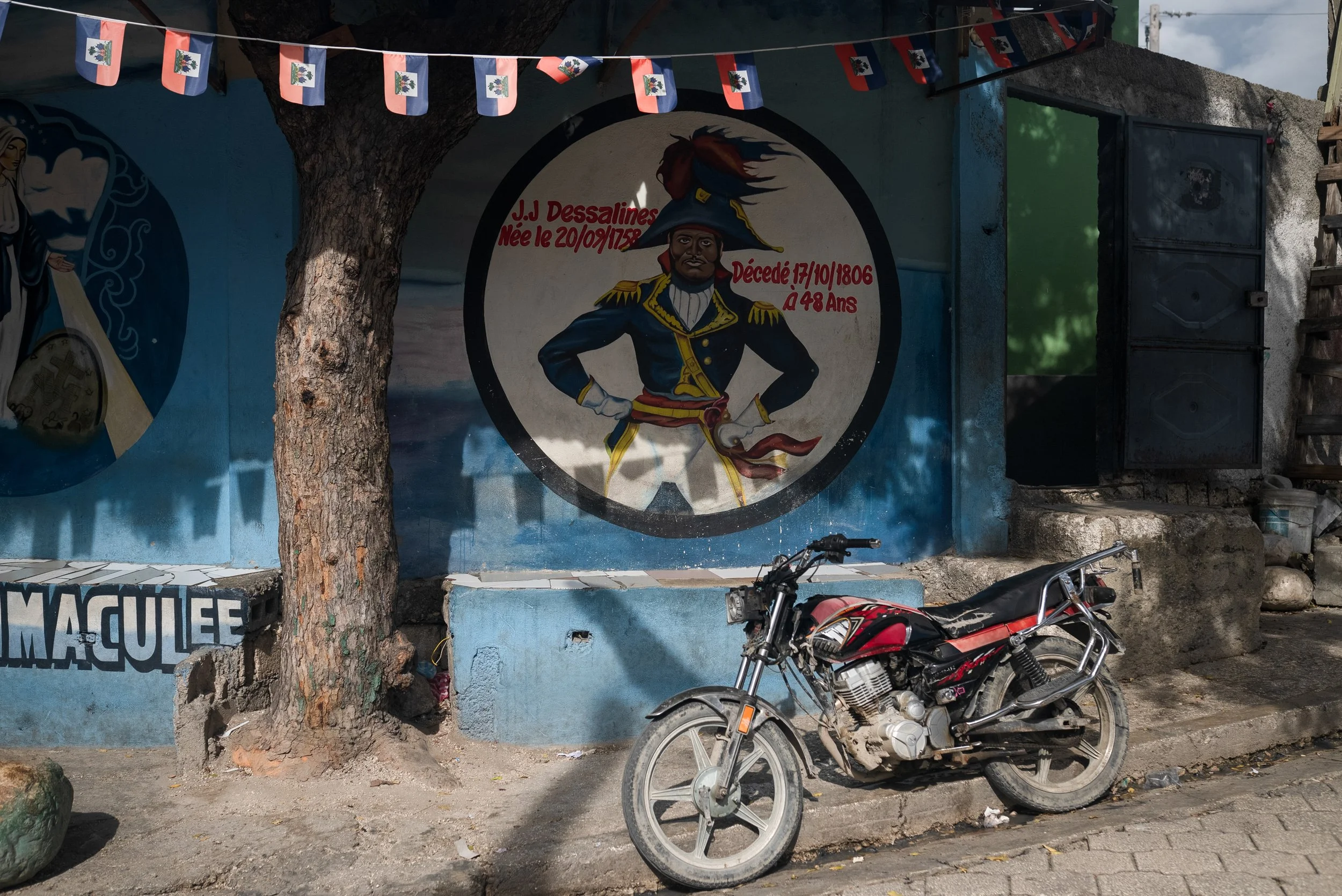 In the neighborhood under the control of G-9 gang leader,  Jimmy Cherizier, "Barbecue", a wall mural depicting Haiti's revolutionary figure and first emperor, Jean-Jacques Dessalines. 2023. 