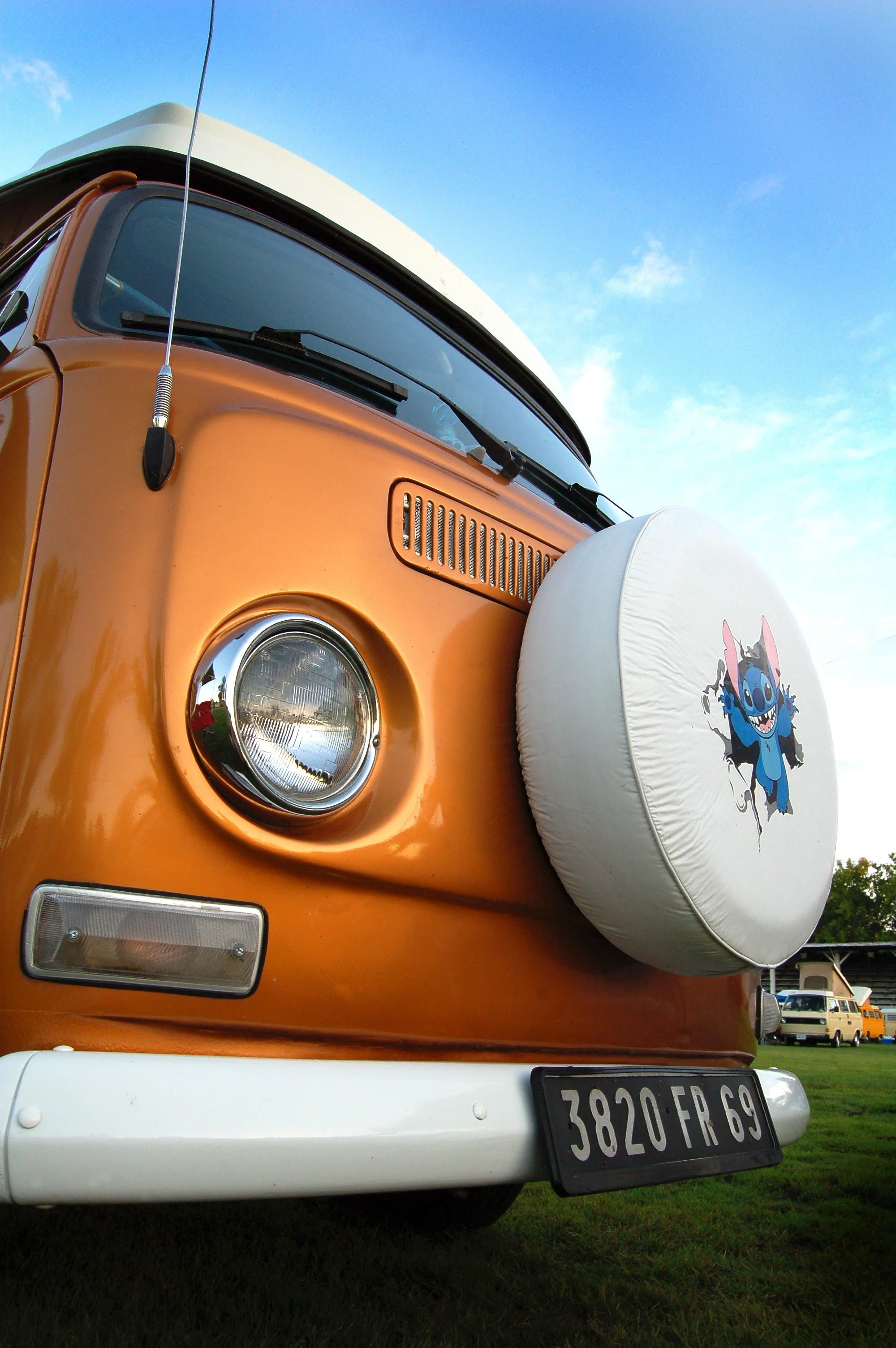 A closeup front view of a VW bus with a white and blue sky in the background.