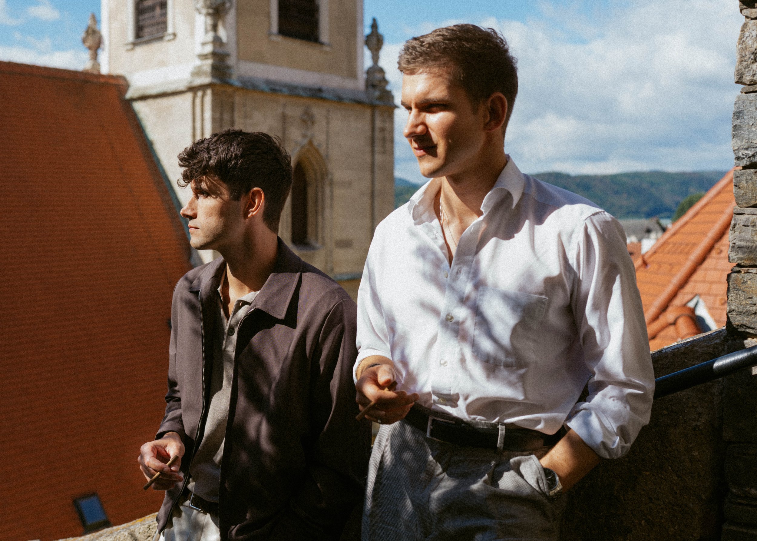 Sonja Malic captures an artistic and cinematic shot of two man leaning against a wall, smoking. Bright light and nostalgic feel.