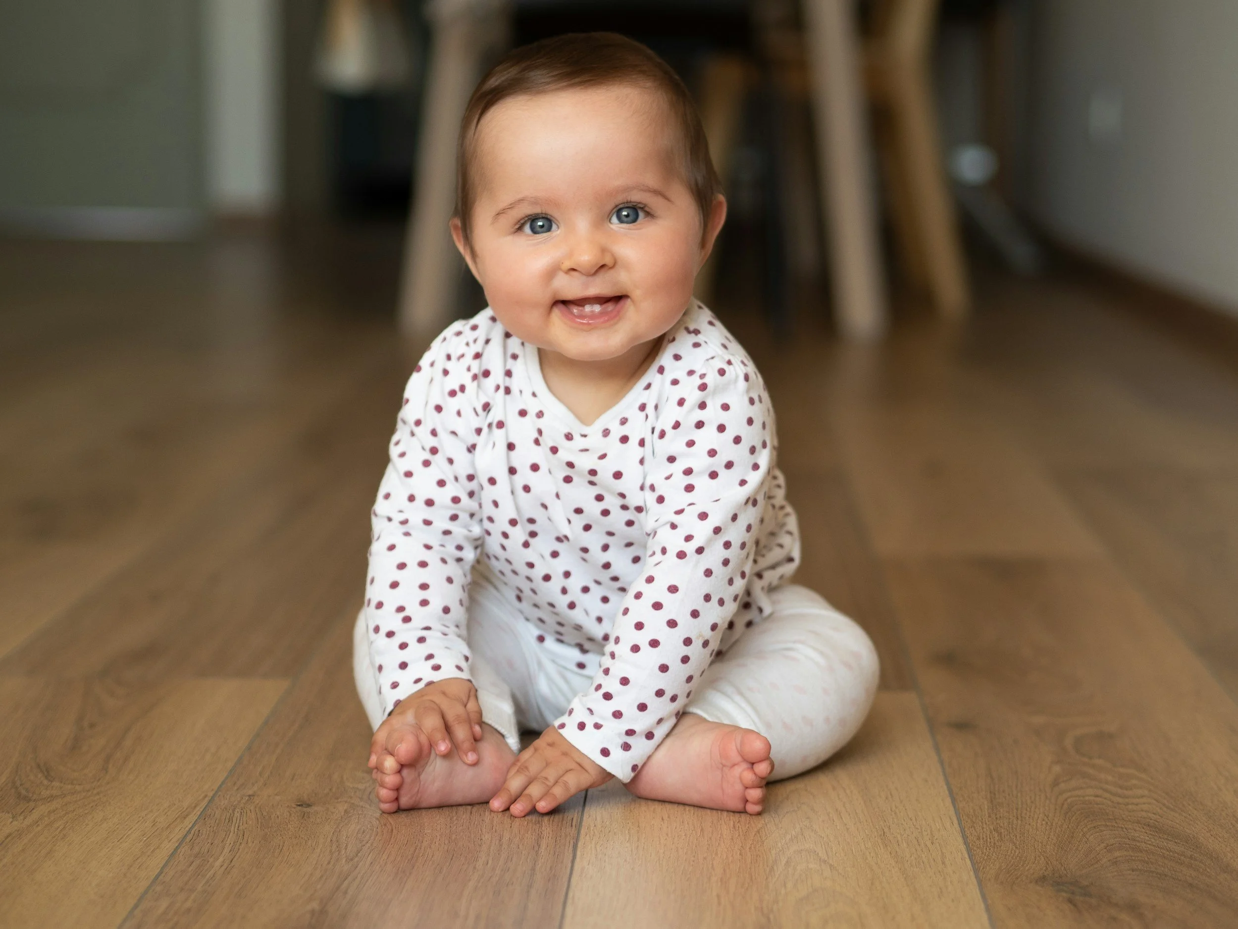 baby with polka  dot shirt sitting and touching feet