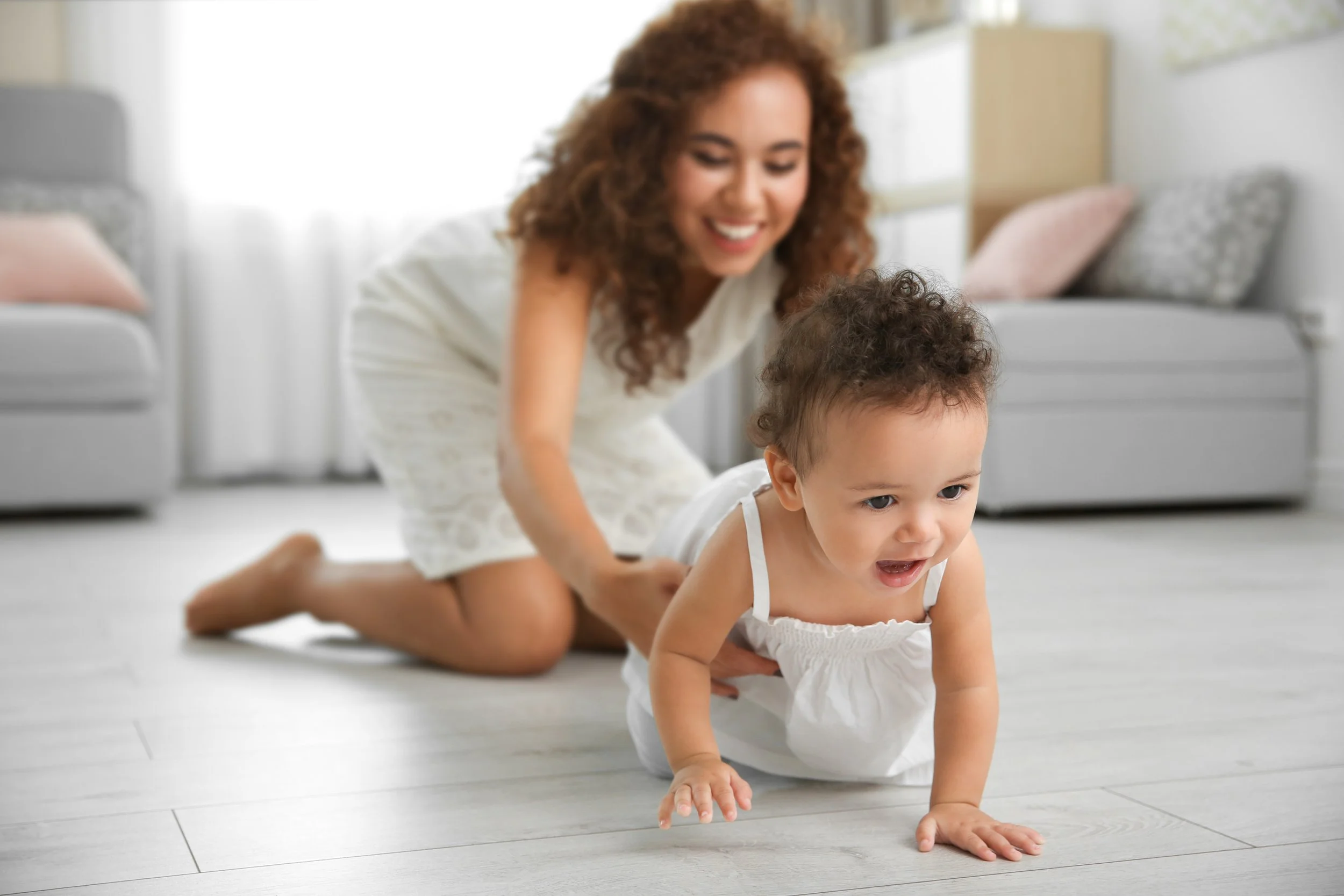Mother on floor encouraging baby to crawl