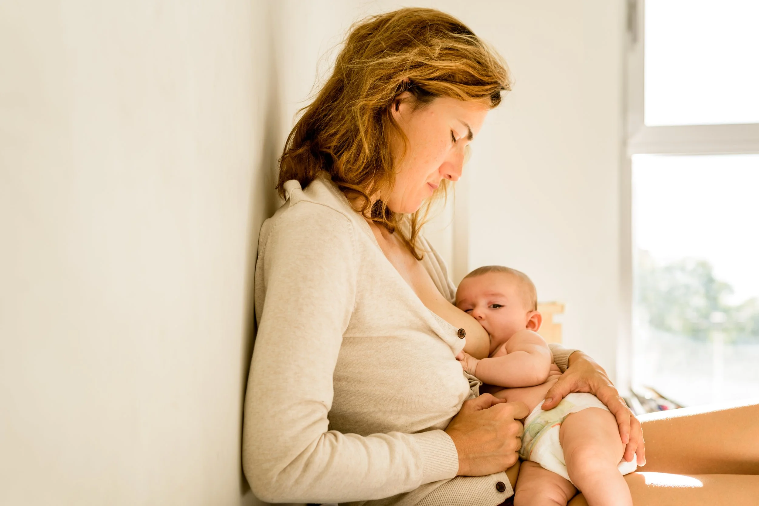 A woman with blonde hair breastfeeding her baby