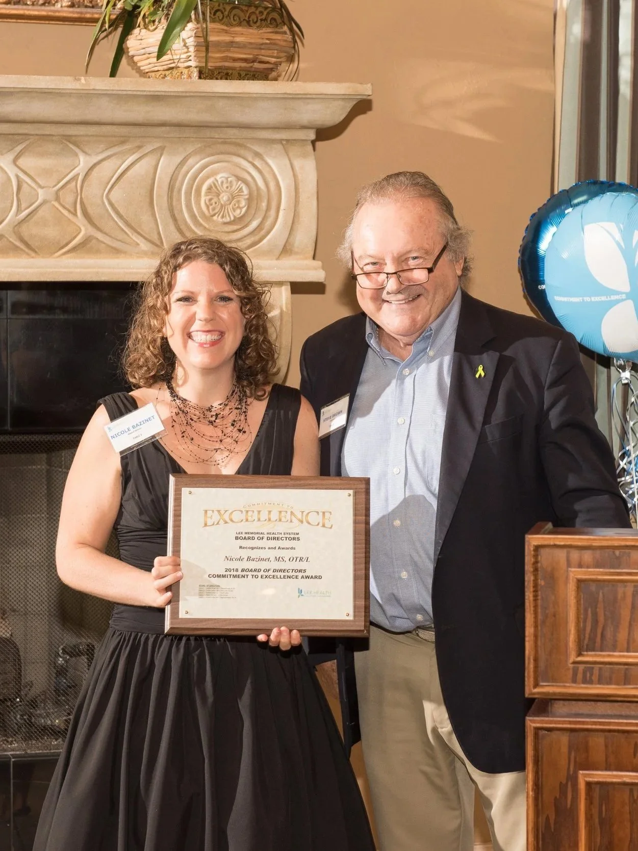 Owner holding an award presented by man standing next to her