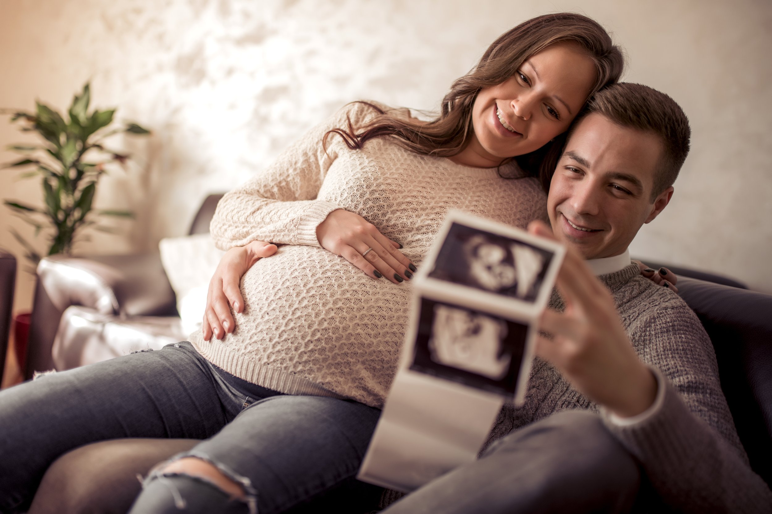 Expectant parents sitting together looking at ultrasound photos