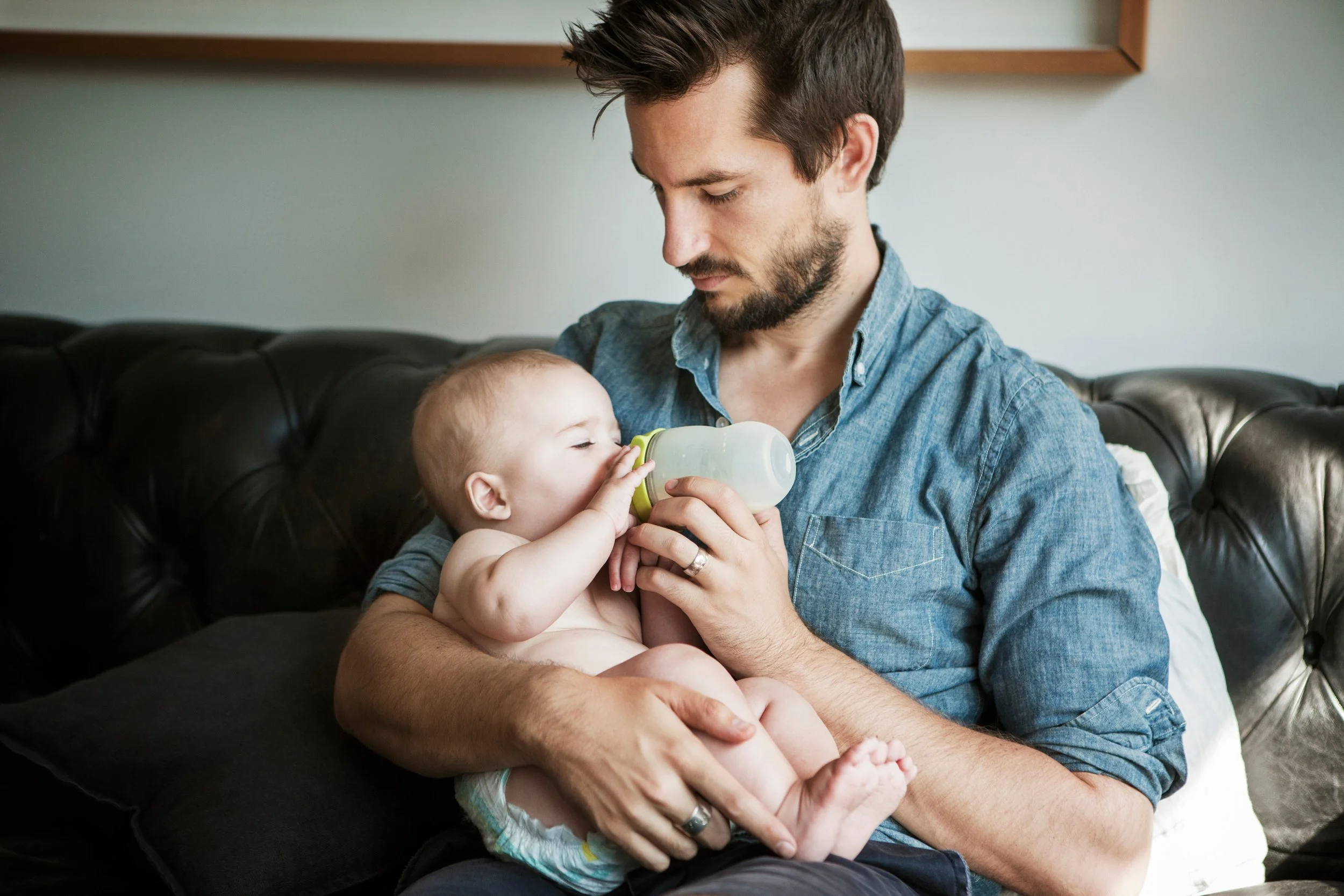 Man holding a baby and feeding him a bottle