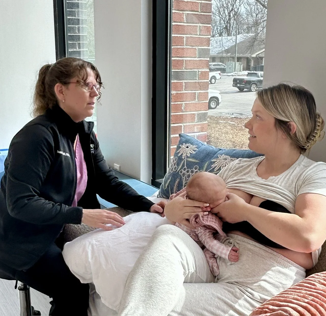 Woman supporting a mother who is breastfeeding her baby