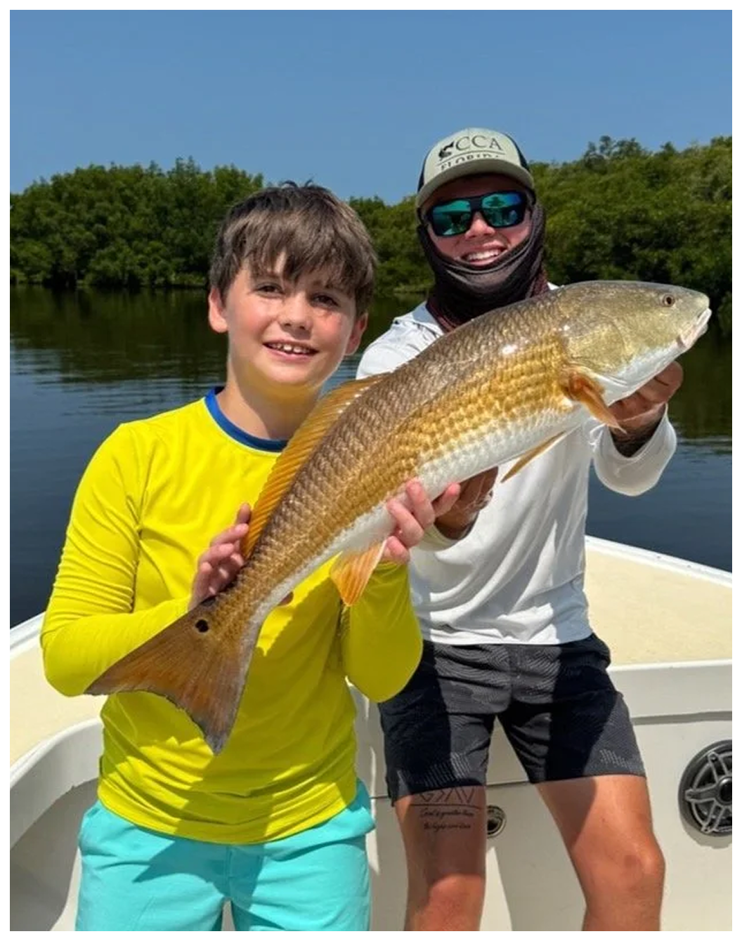 Fishing charter group holding a golden fish on a boat.