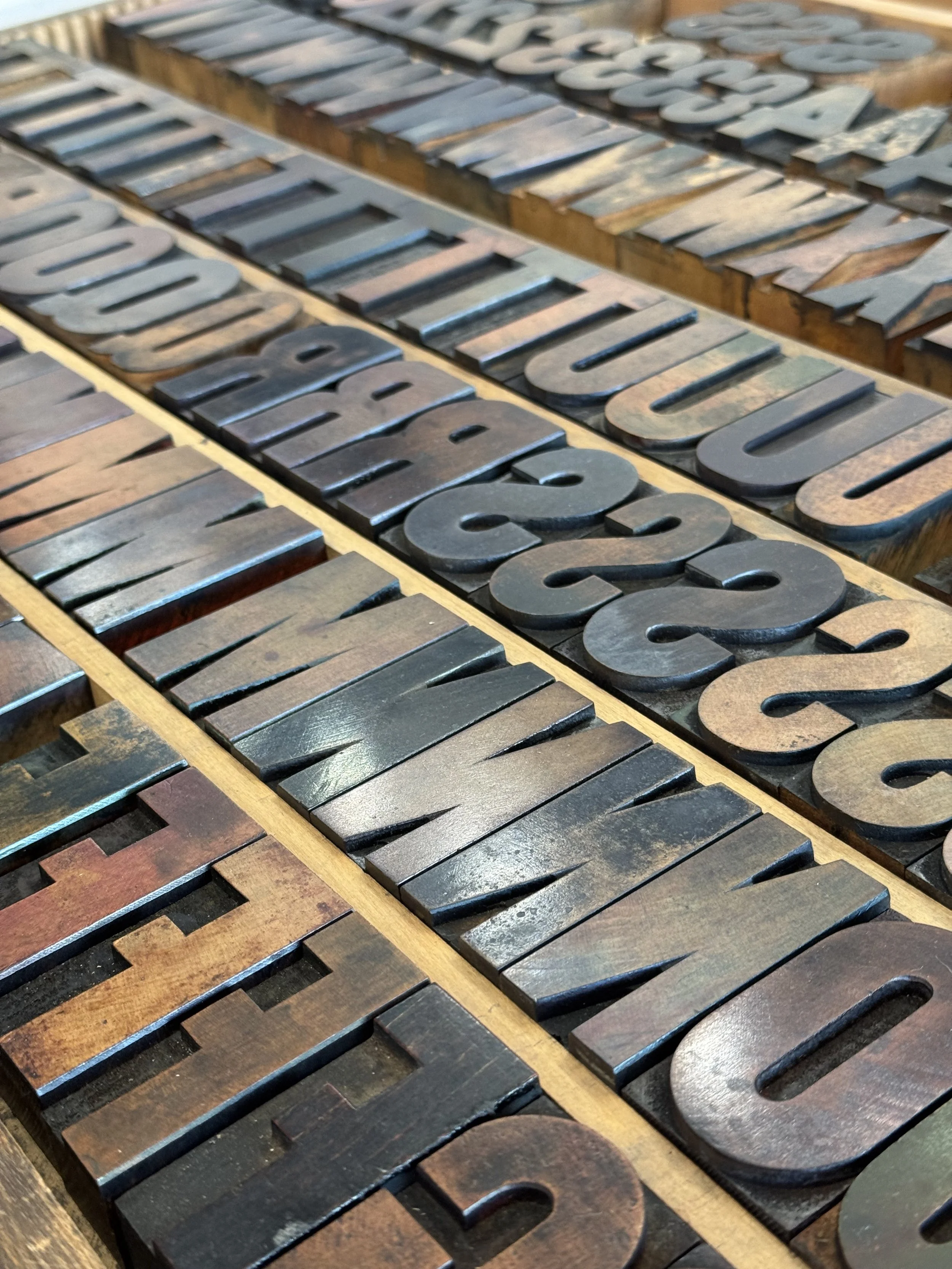 Close-up of wooden letterpress blocks arranged to spell out words, with some blocks displaying letters and numbers.