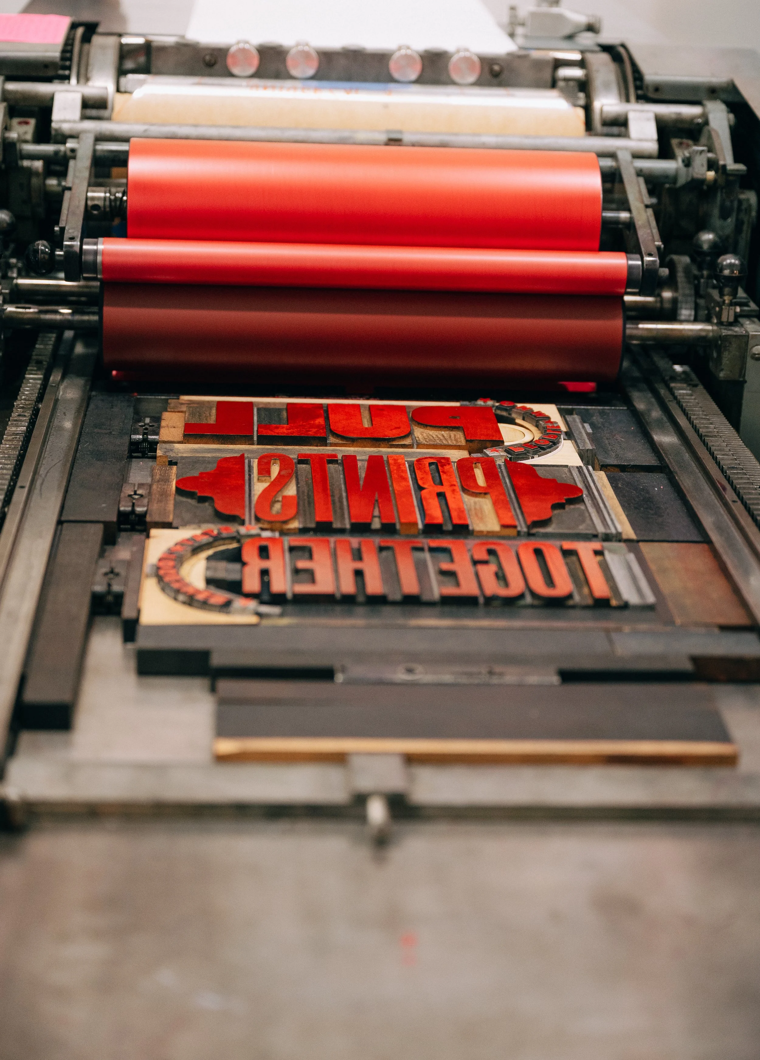 A printing press with red and black ink printing the words "TOGETHER PUSH" on a sign