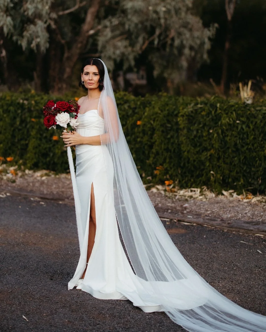 Bride wearing an expertly altered and tailored wedding gown with a fitted silhouette and high slit, showcasing professional bridal alterations and wedding dress tailoring services.