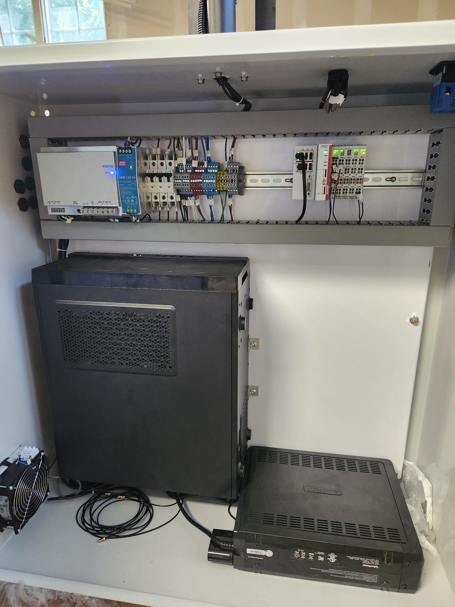 Electrical control panel with various circuit breakers, switches, and electronic devices, mounted inside a metal enclosure.