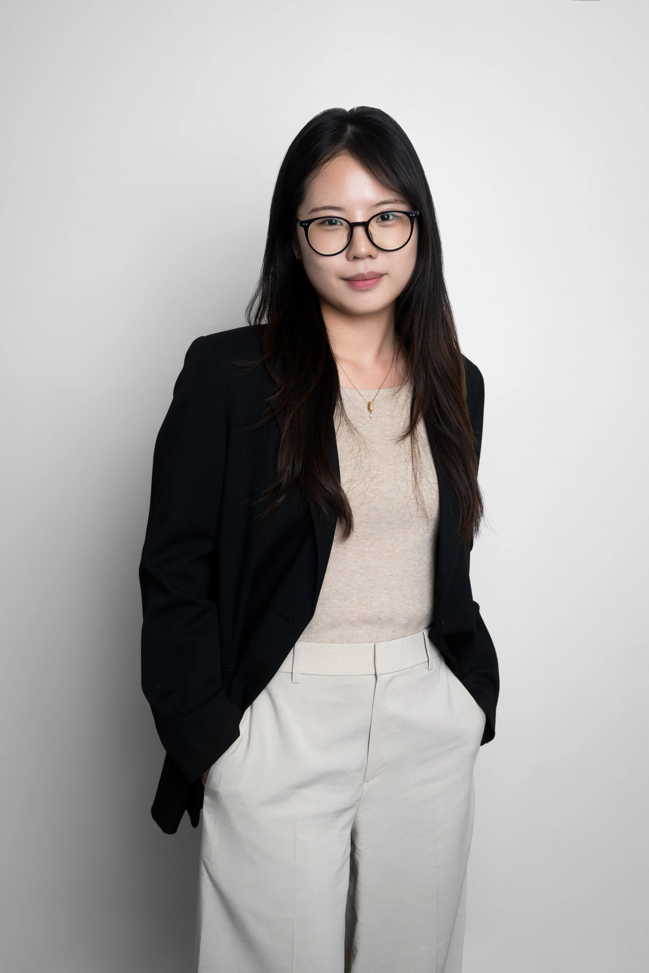 Person with long hair and glasses wearing a white blouse, smiling at the camera. seongyeon song