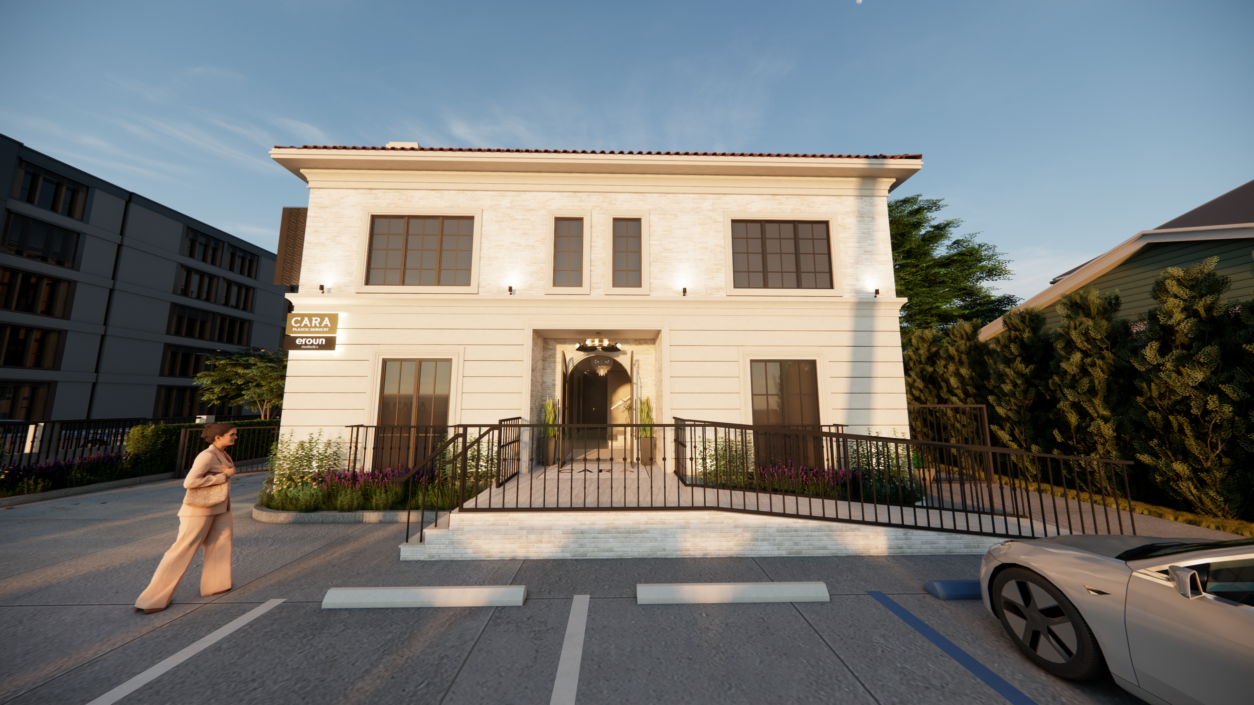 A modern two-story white building with large windows, front entrance with steps, landscaped front yard, and a person walking in the parking lot. A luxury car is parked on the right side, and neighboring buildings are visible on both sides. The sky is clear with some clouds.