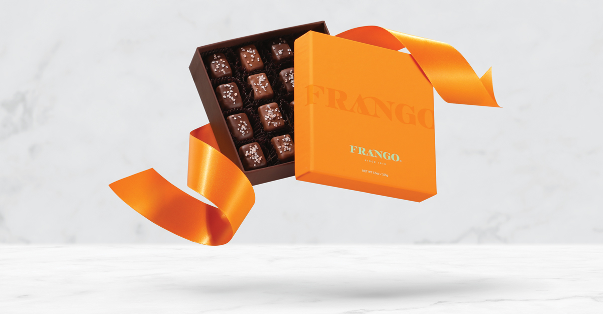 Orange Frango chocolate box with lid open, showing chocolate truffles decorated with sea salt, and an orange ribbon.
