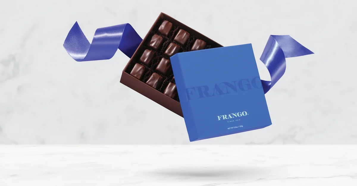 Blue Frango chocolate box with open lid, showing rows of chocolates, and a blue ribbon against a light background.