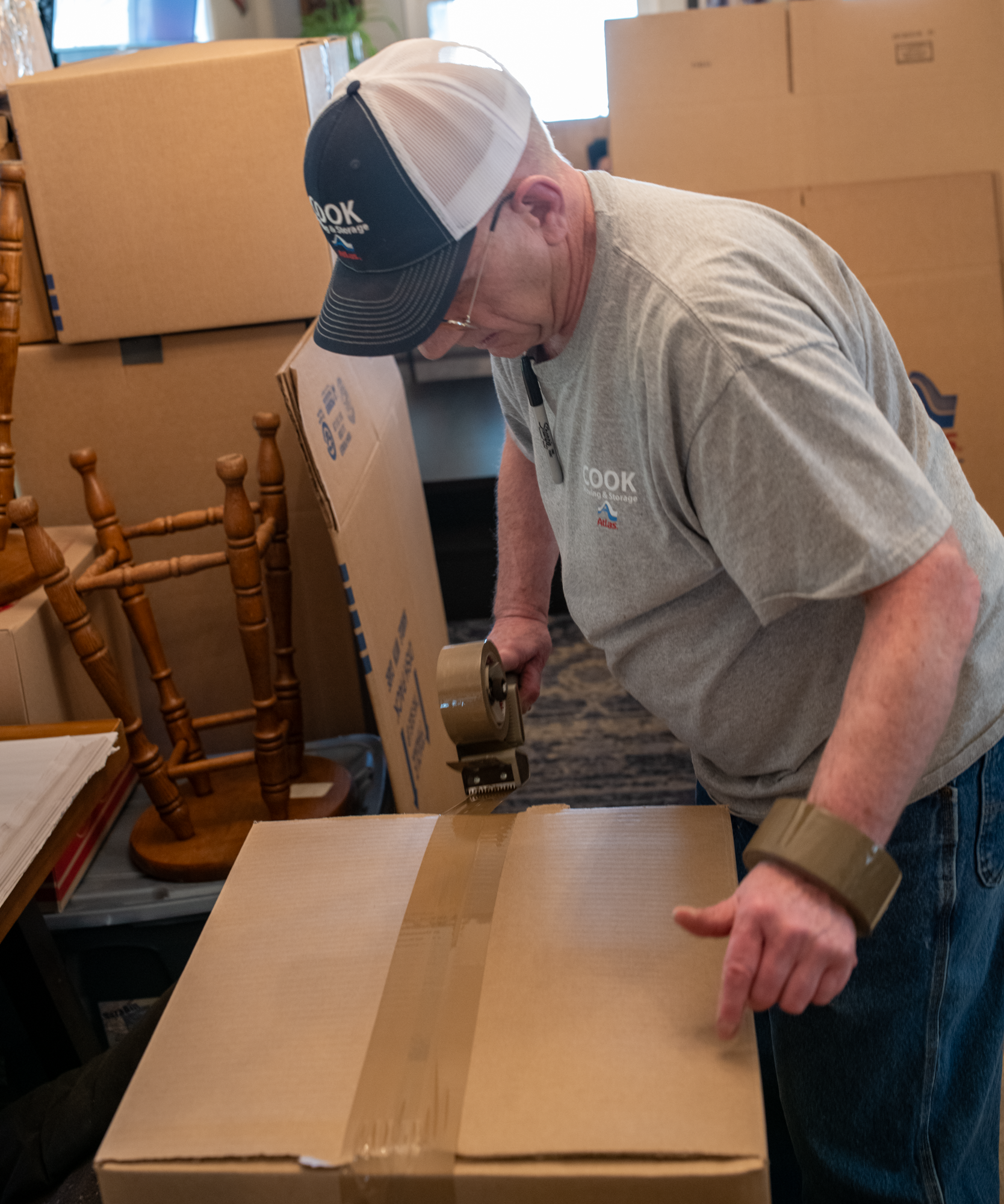 A man taping the top of a packed box.