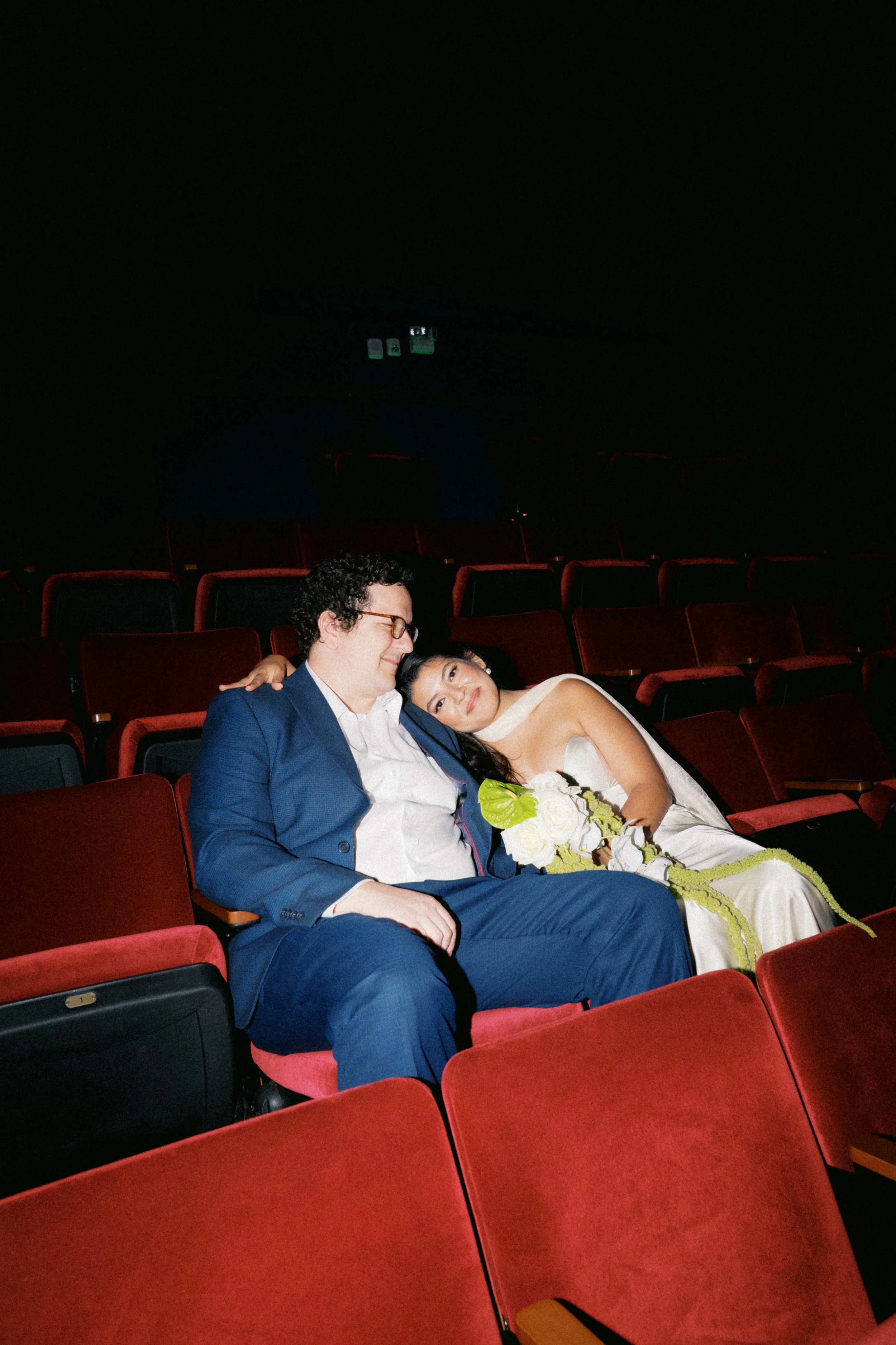 Newly married couple sitting together in vintage movie theater seats