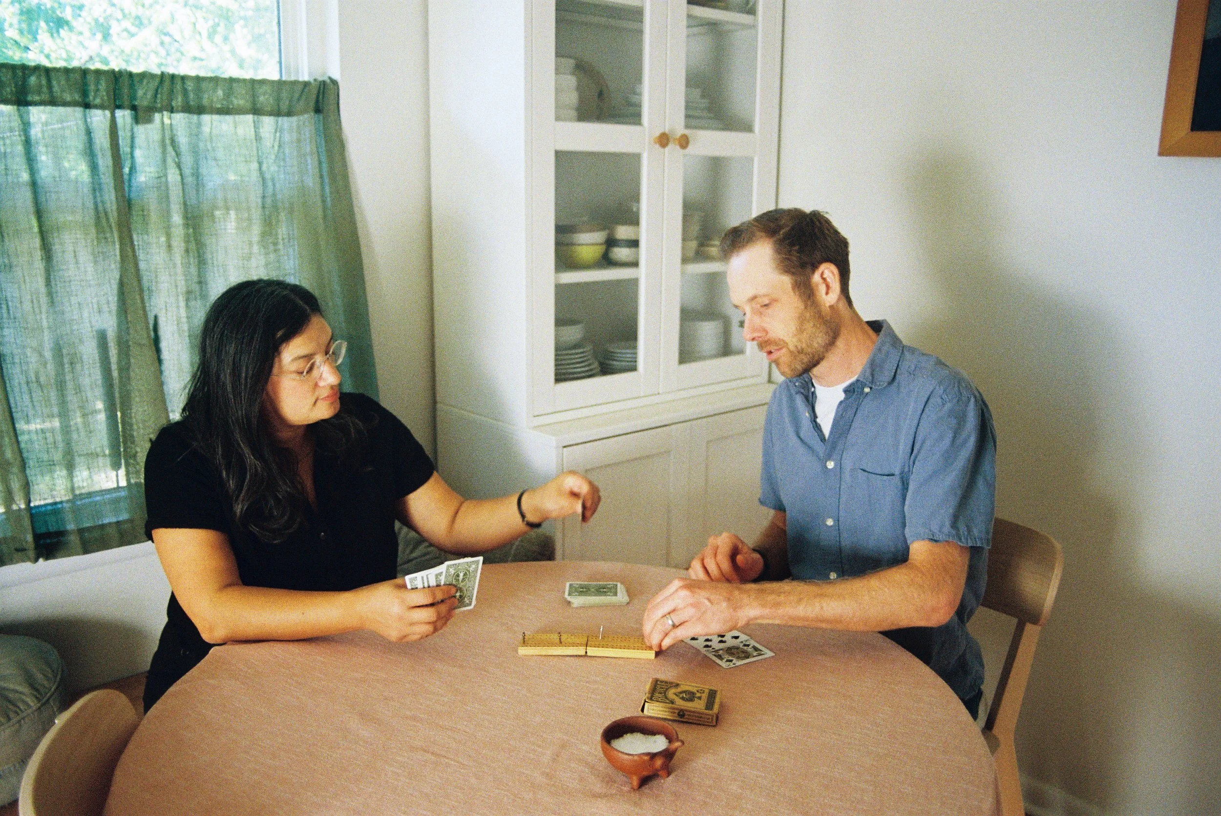 Couple playing cards at home in Fort Worth on a Sunday afternoon, shot on 35mm film