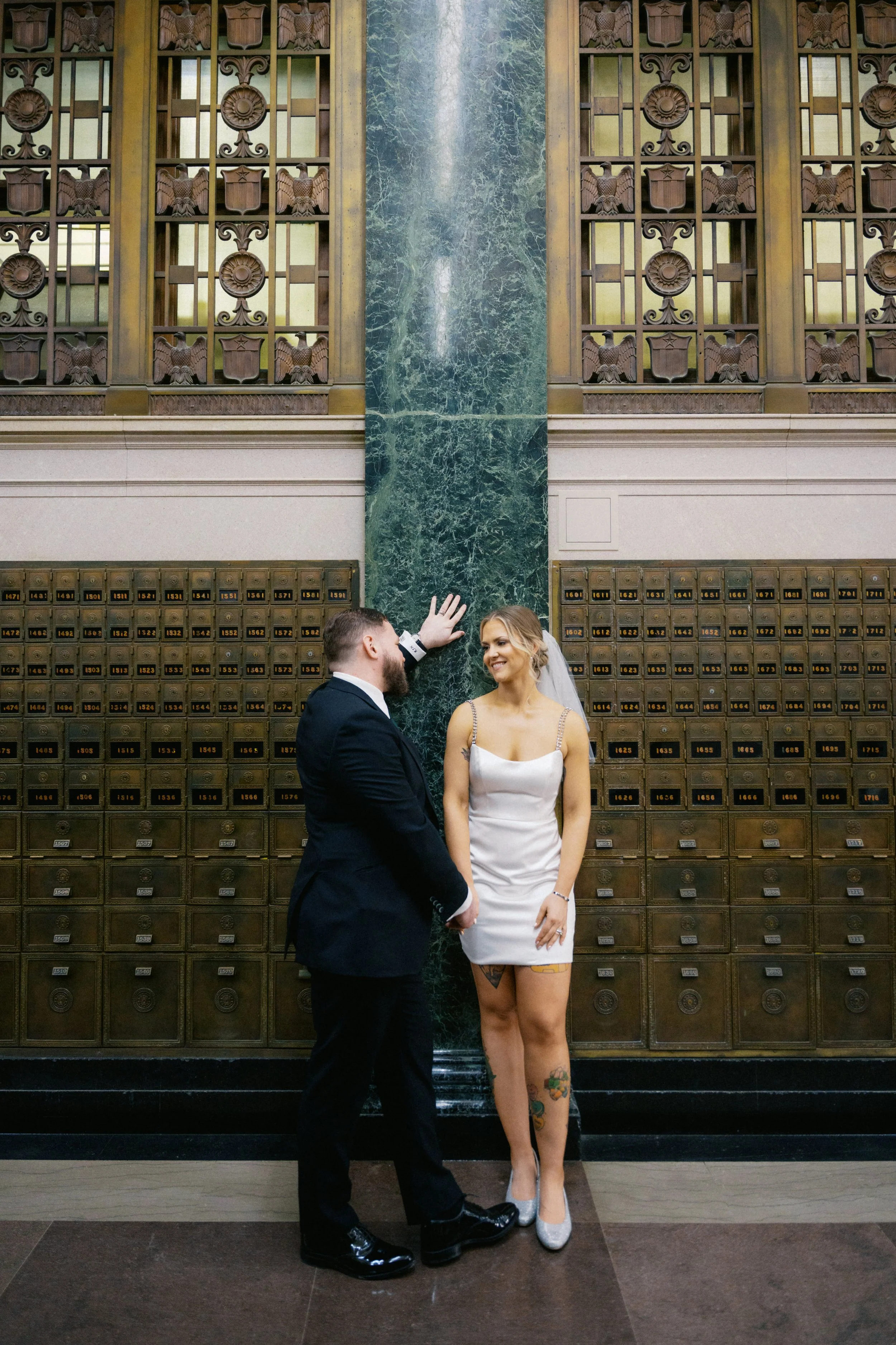 Bride and groom standing beneath historic architecture in Fort Worth