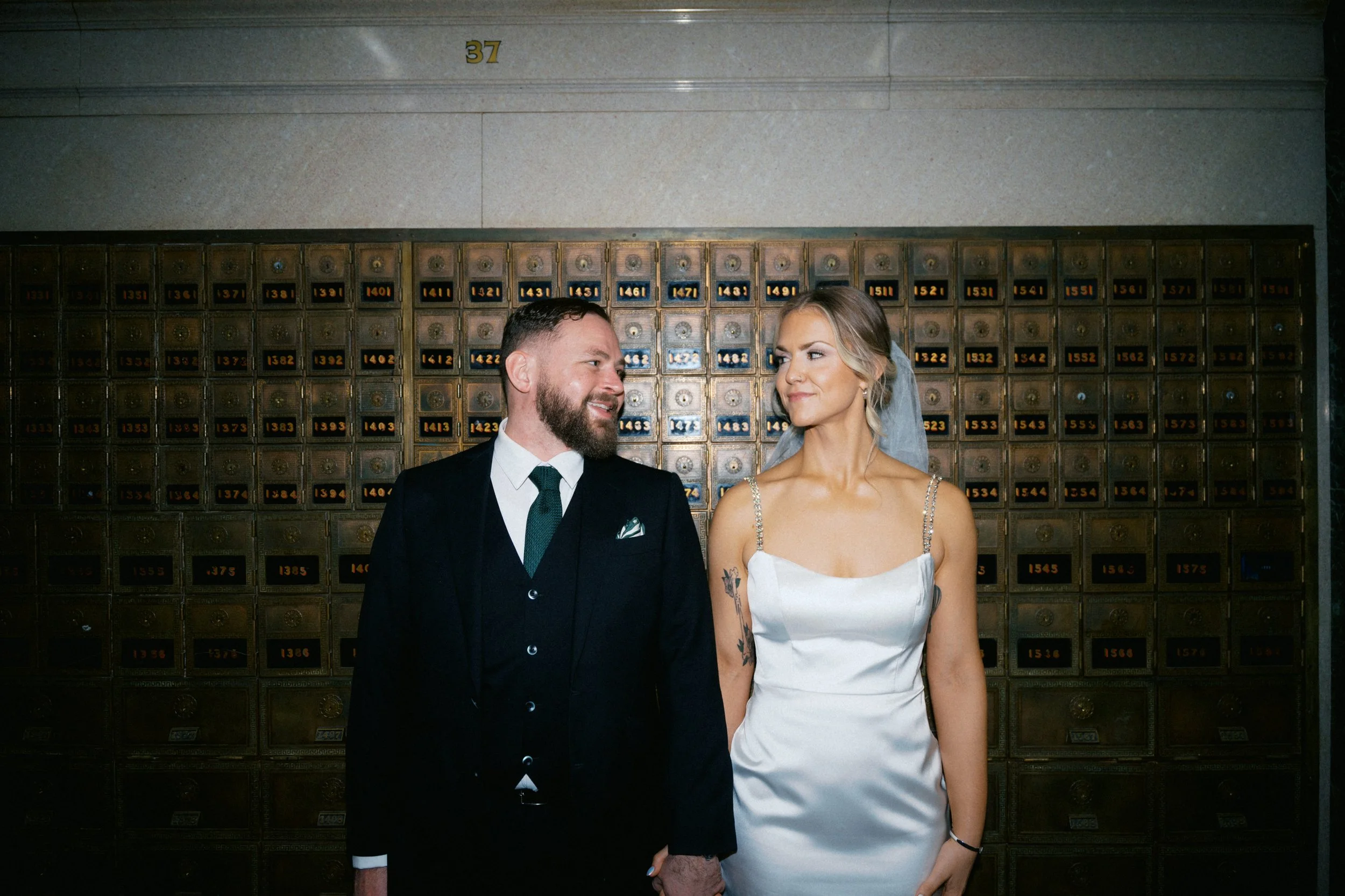 Bride and groom standing beneath historic architecture in Fort Worth