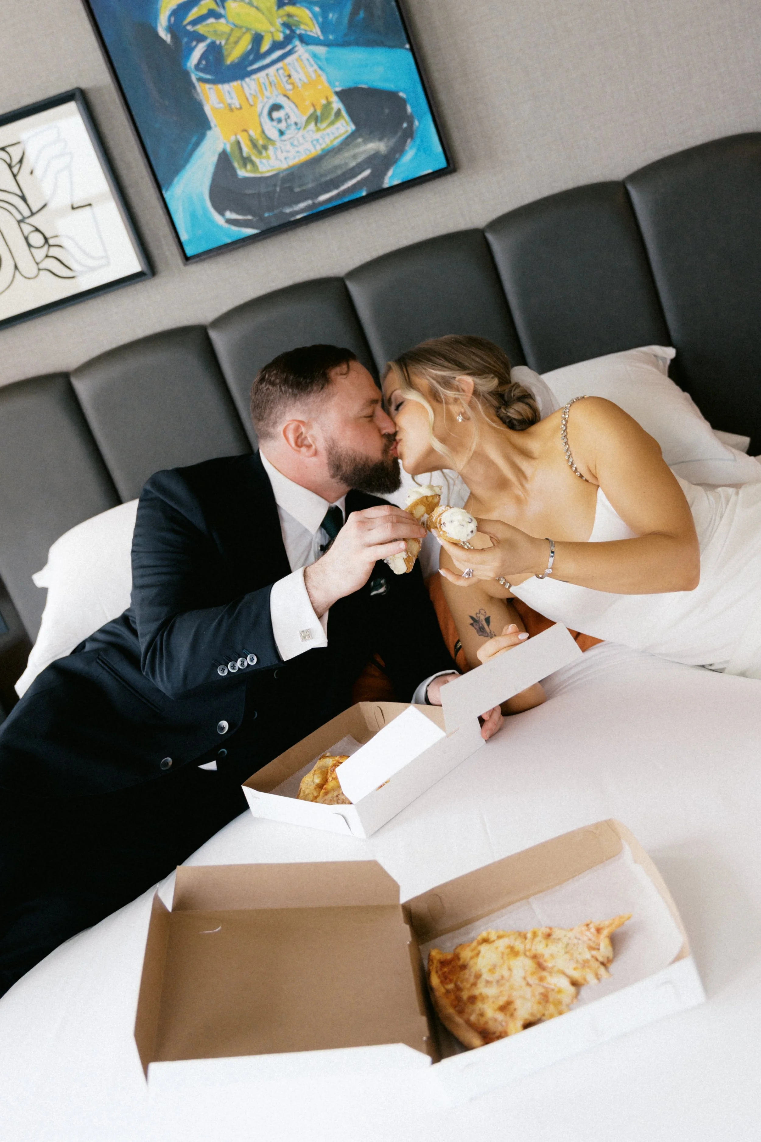 Couple eating pizza in bed at Kimpton Harper Hotel