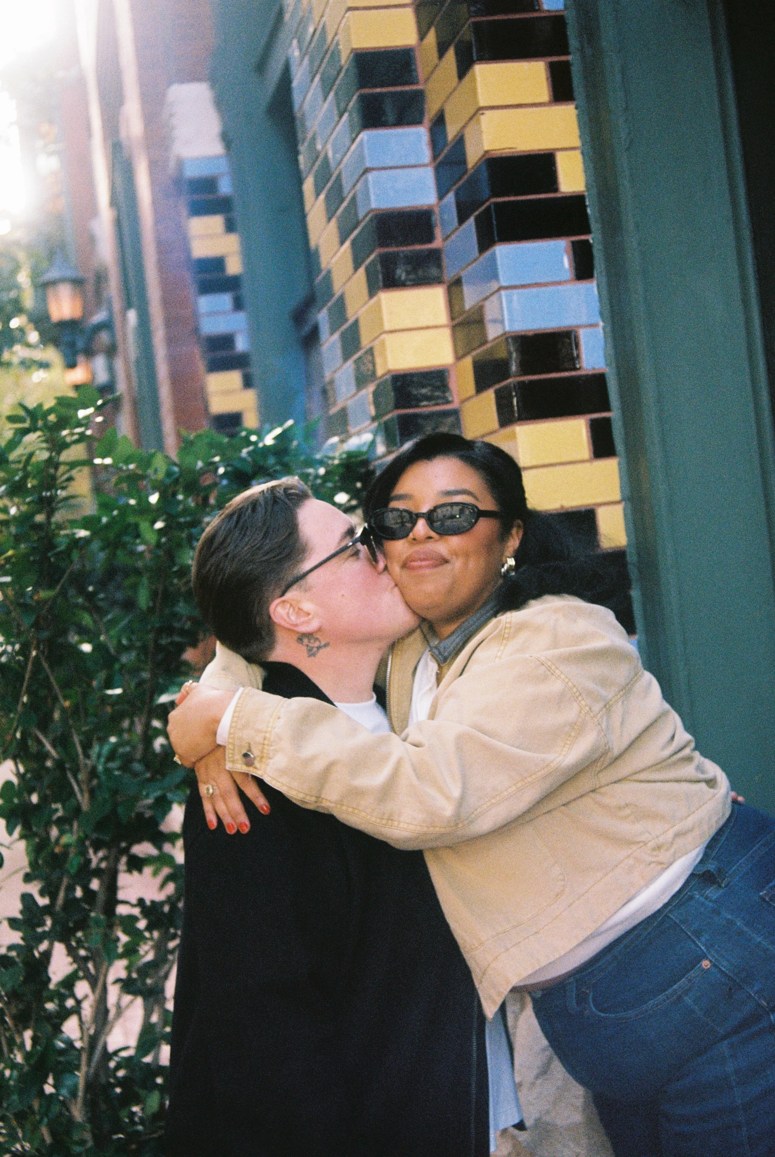 Close-up film photograph of couple kissing on the cheek in Sundance Square, Fort Worth