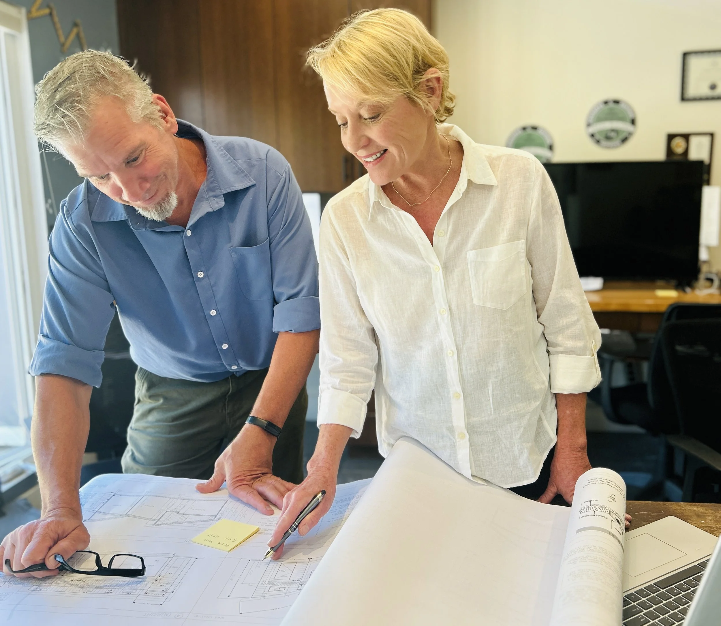 Elite construction contractor and Santa Cruz Cabinet designer reviewing architectural blueprints in our Santa Cruz office, collaborate on a remodeling project.