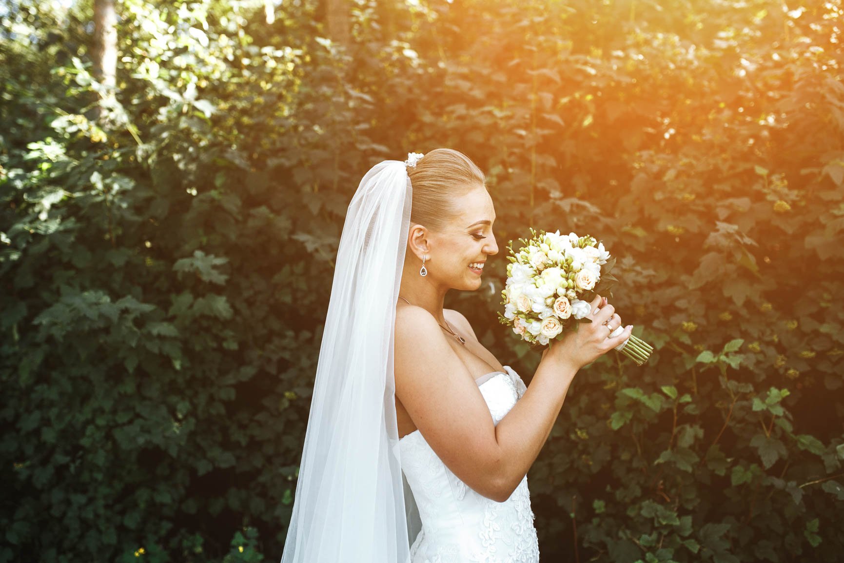 woman-wedding-dress-smiling-smelling-bouquet.jpg
