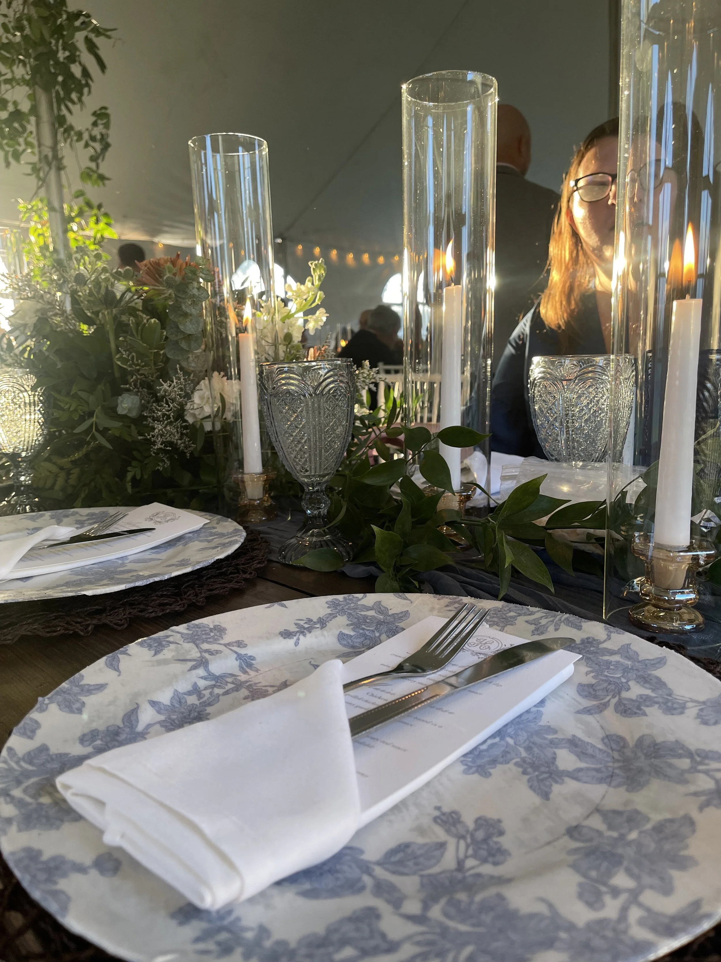 Wedding reception tablescape with candlelight and dusty blue floral centerpiece