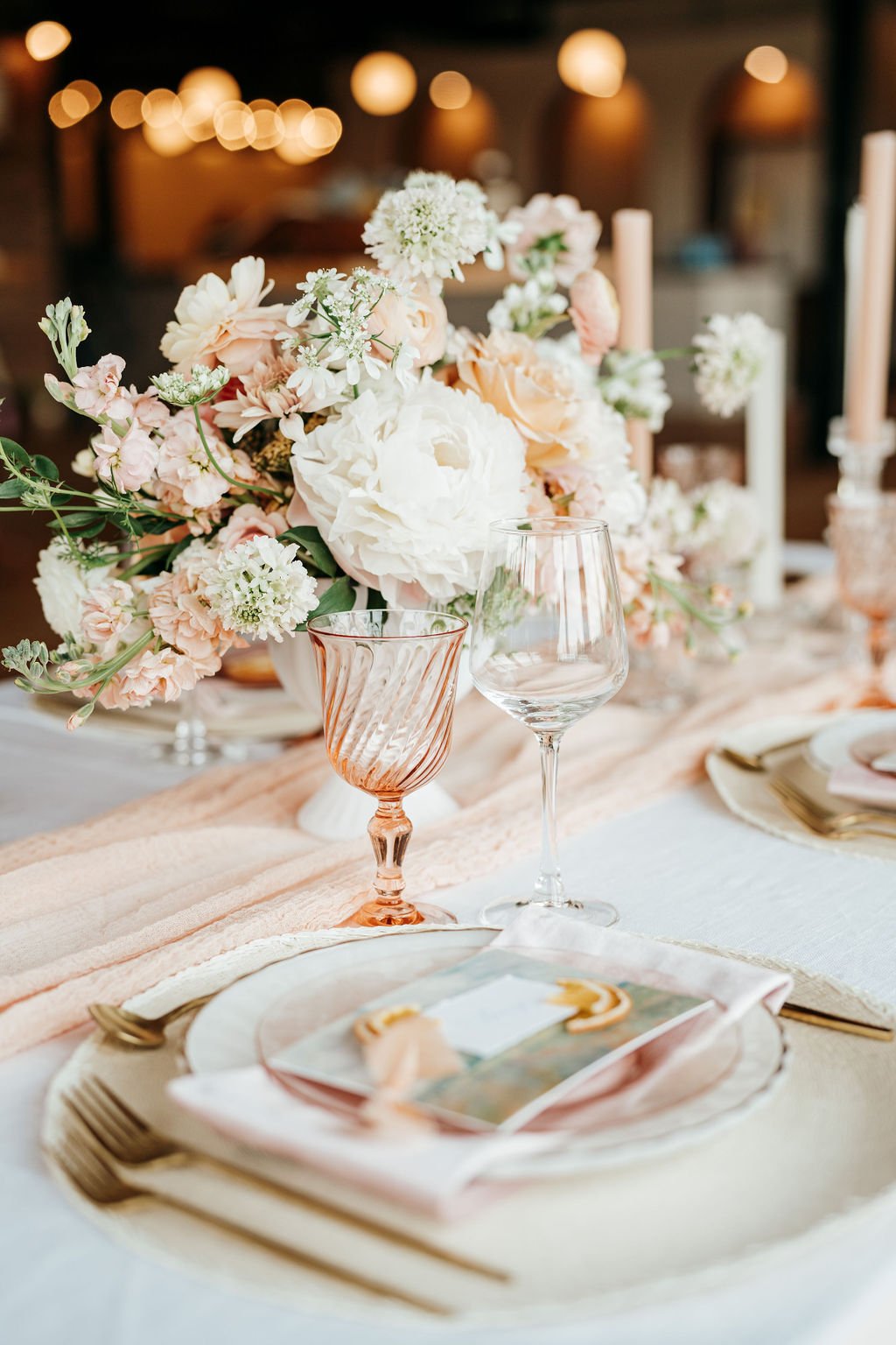 Elegant wedding reception place setting with blush napkin, custom place card, and floral centerpiece