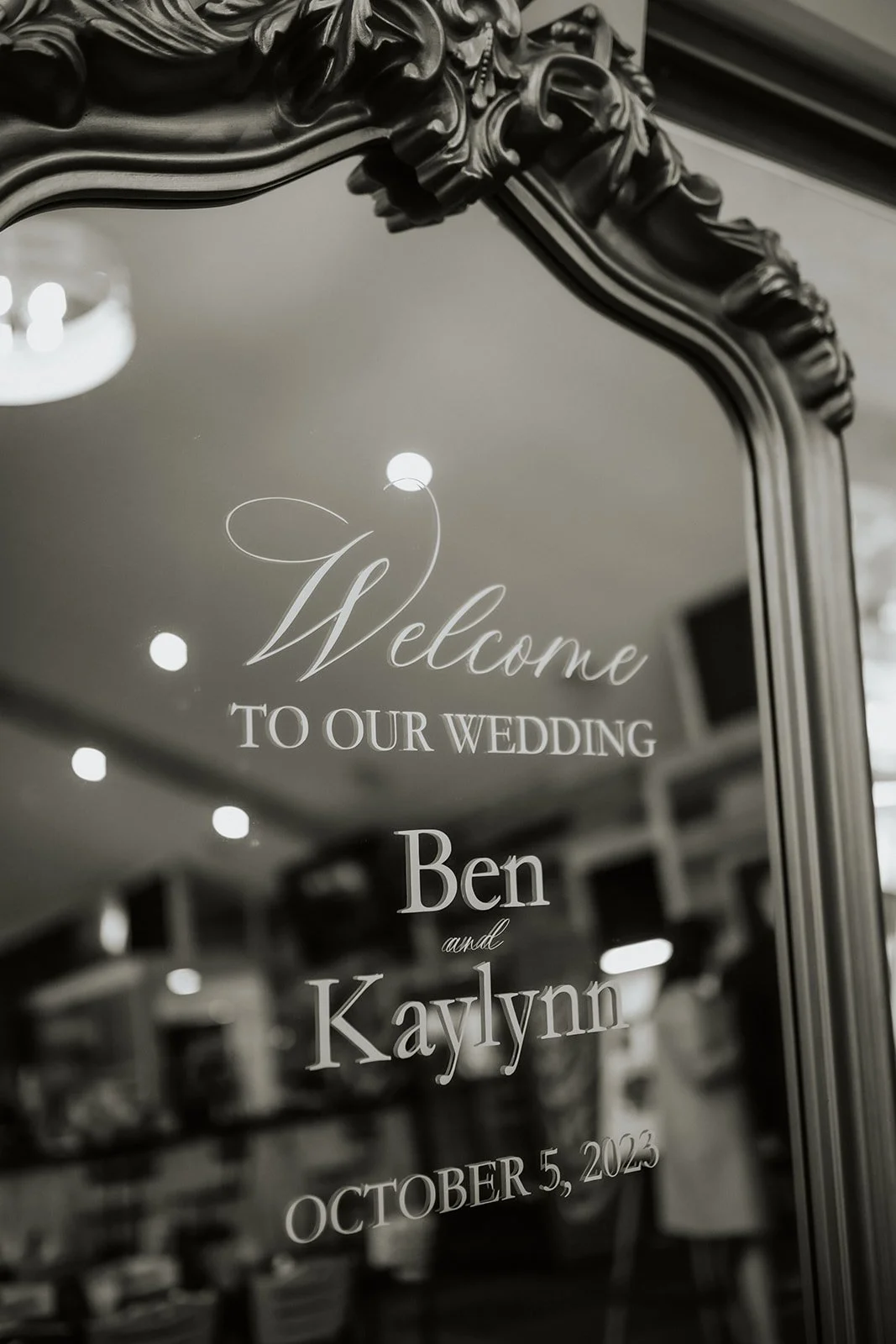 black and white photo of welcome wedding sign on vintage mirror