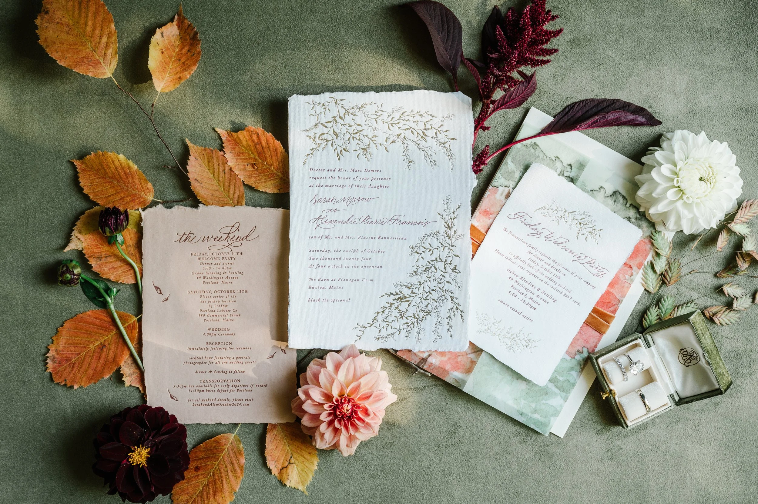 Custom wedding invitation suite flat lay with greenery and ribbon details