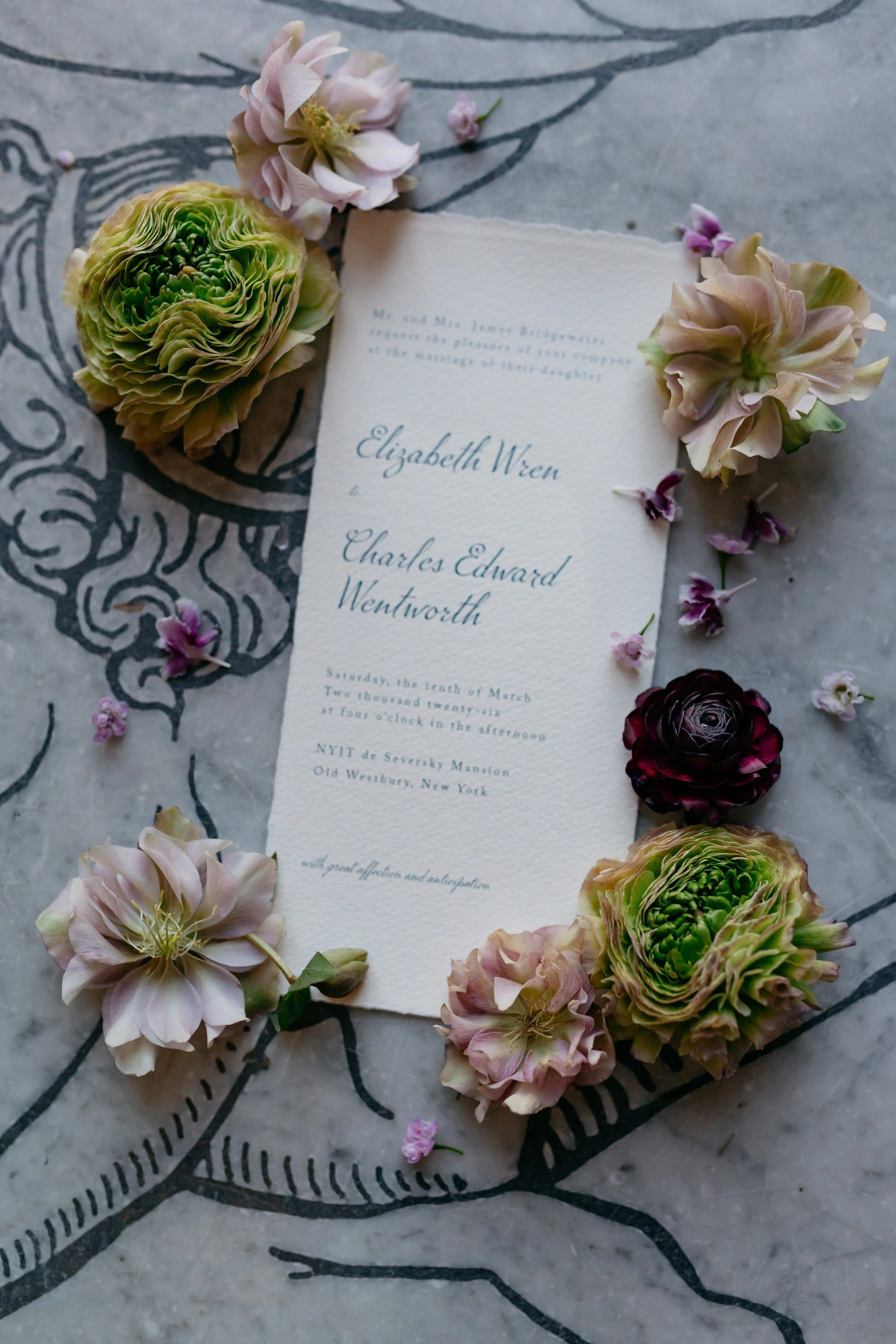 A Jane Austen inspired wedding invitation card surrounded by pink, cream, and green flowers on a decorative black and white surface.