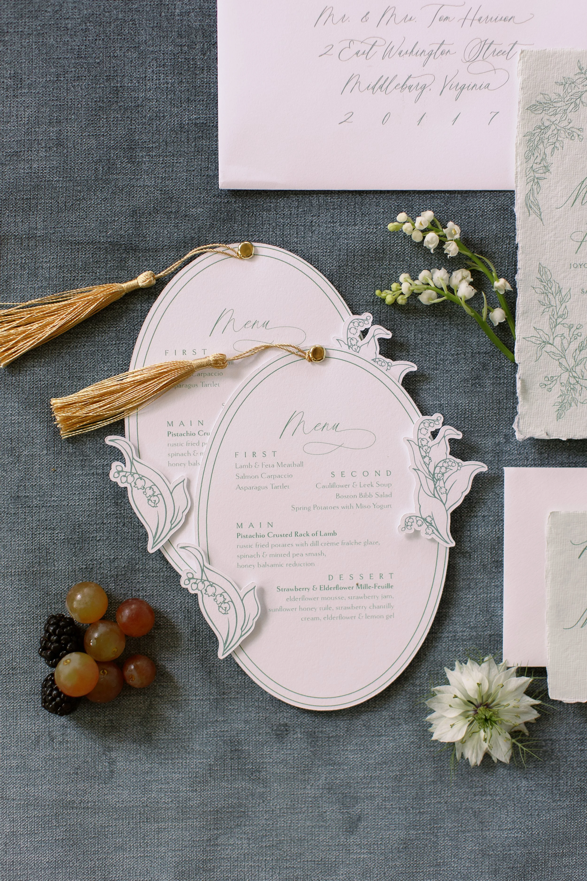 oval wedding menus with gold tassel and lily of the valley flowers