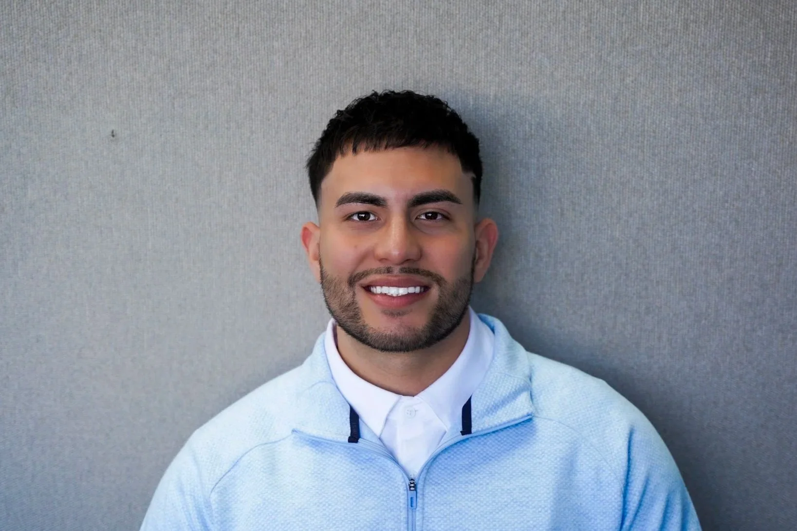 Man in black shirt sitting on outdoor stairs, smiling.