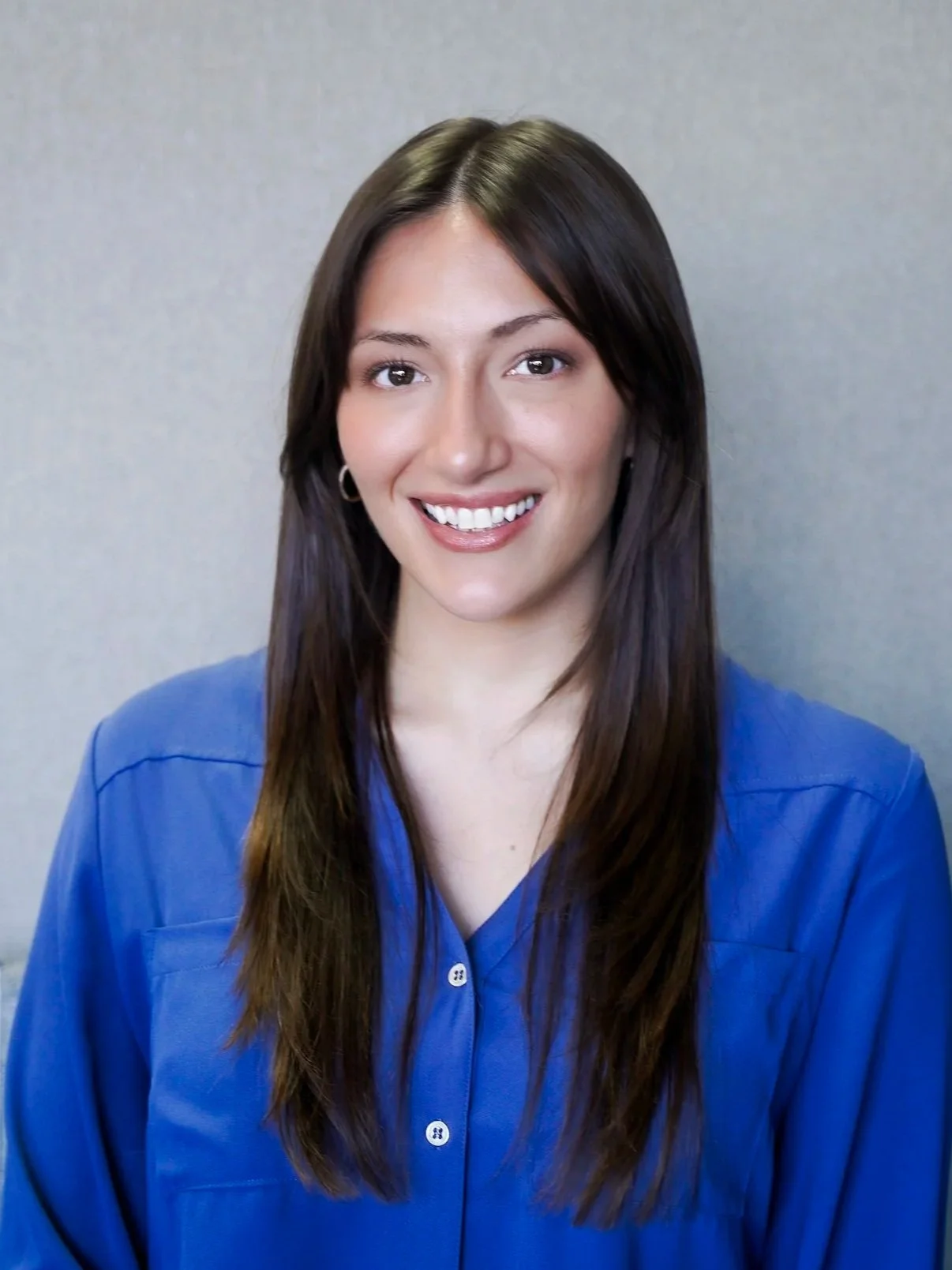 Person sitting on concrete steps, wearing a white shirt and jeans, smiling.
