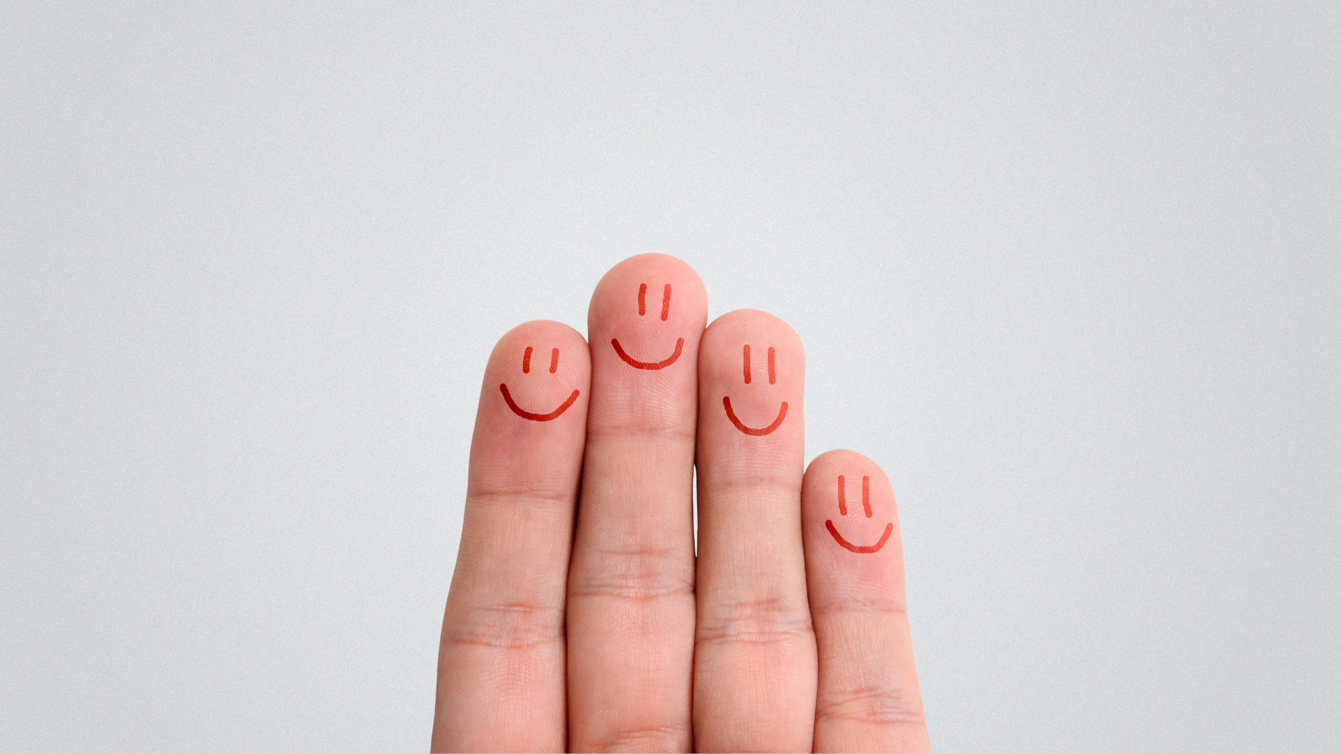 Four fingers with faces drawn on the tips, all smiling, on a light gray background.