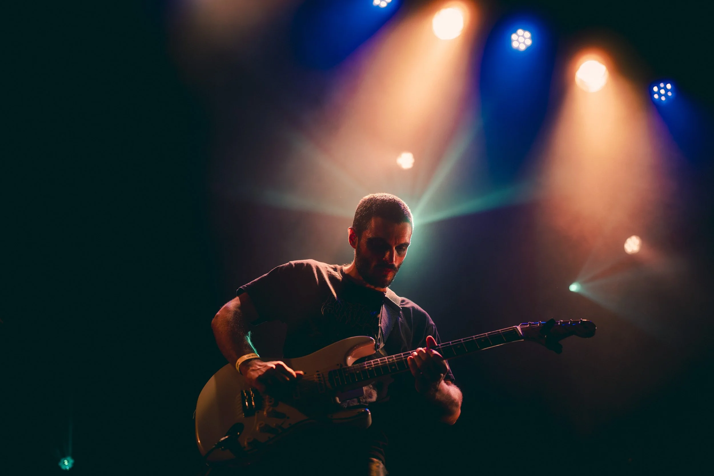 Un musicien jouant de la guitare électrique sur scène, éclairé par des lumières colorées