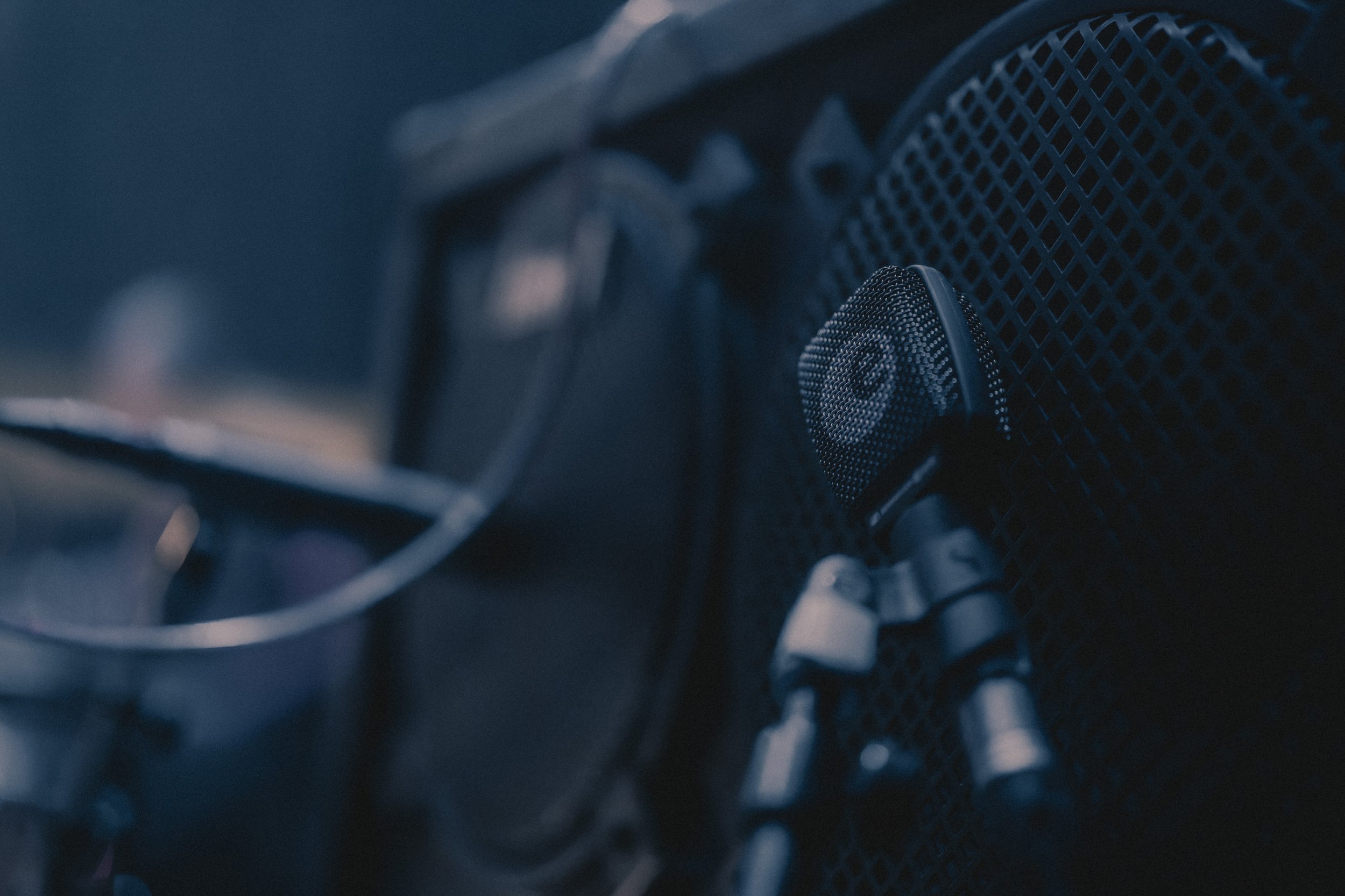 Un microphone placé sur une grille, avec un fond flou, probablement dans une cabine d'enregistrement ou un studio audio.