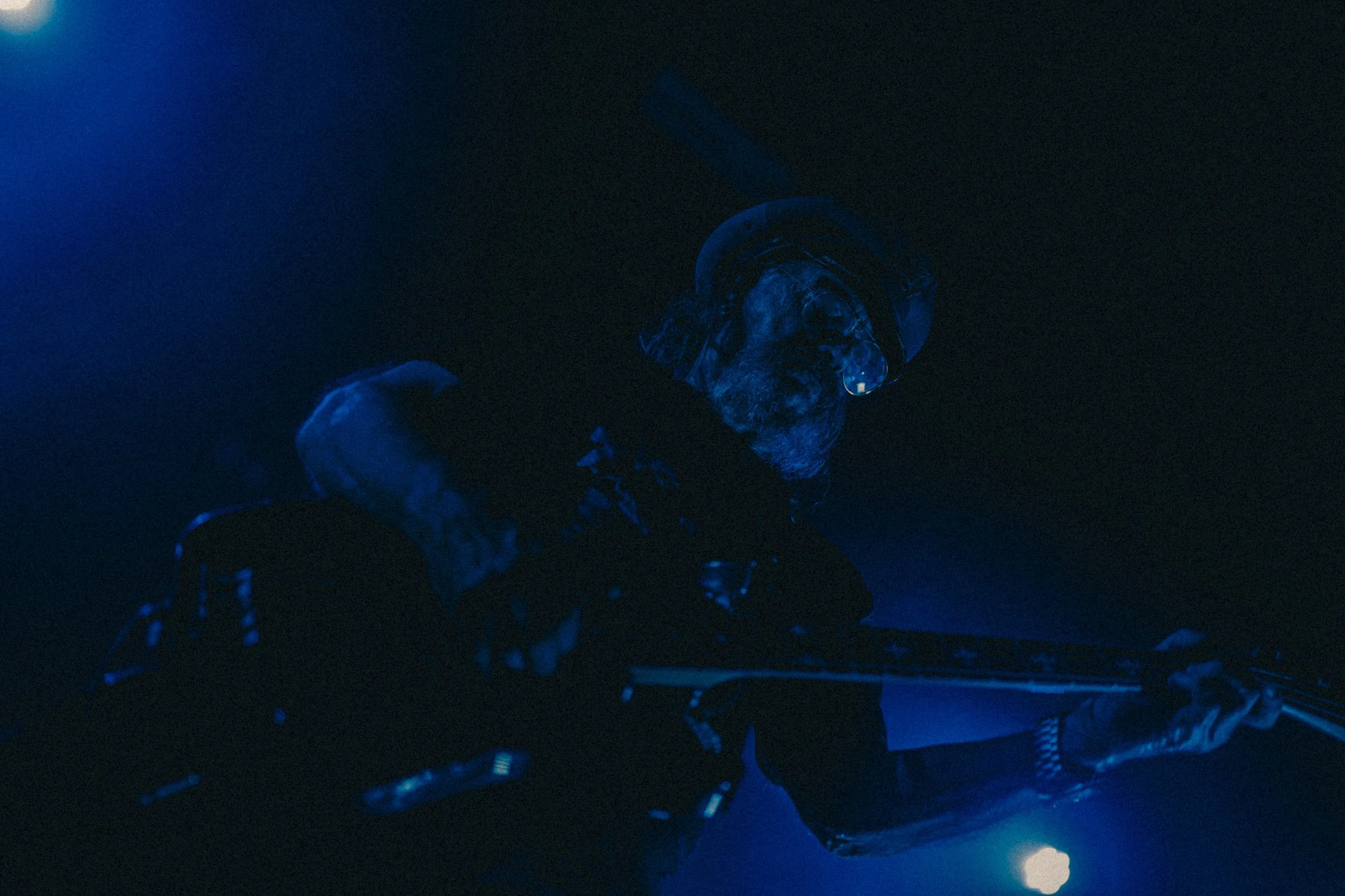 Une personne portant des lunettes de plongée et un casque de protection, dans un environnement sombre avec une lumière bleue.