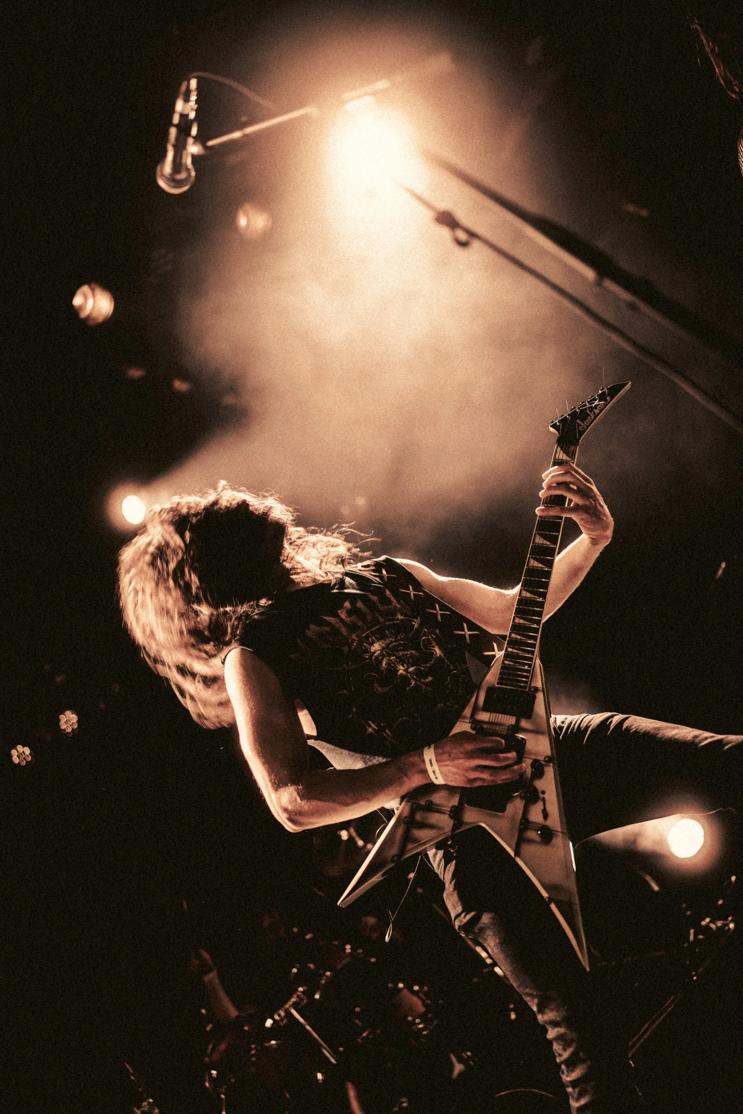 Musicien jouant de la guitare électrique sur scène sous un éclairage chaud.