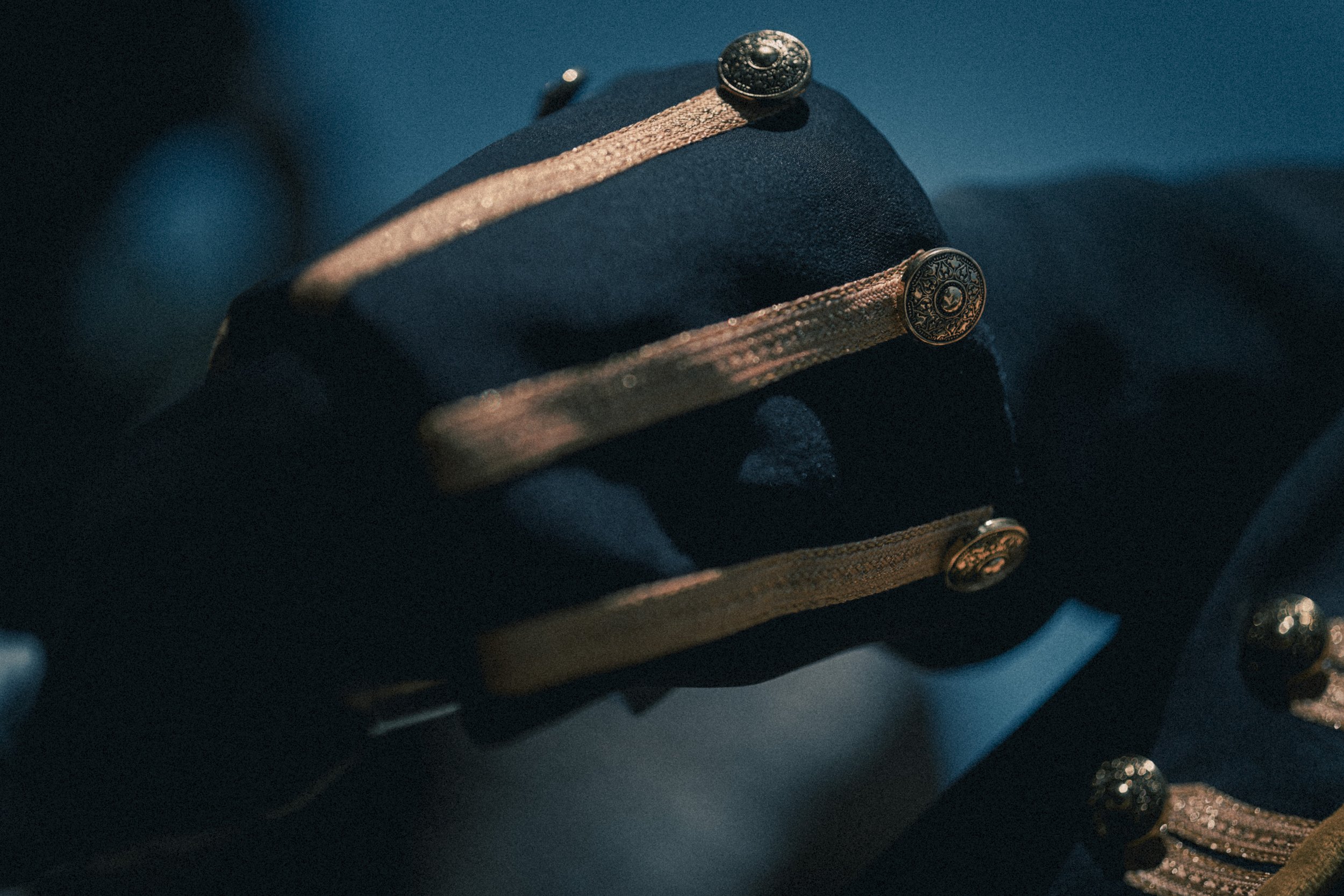 Une montre-bracelet posée sur un support noir avec une bande métallique et des boutons décoratifs.