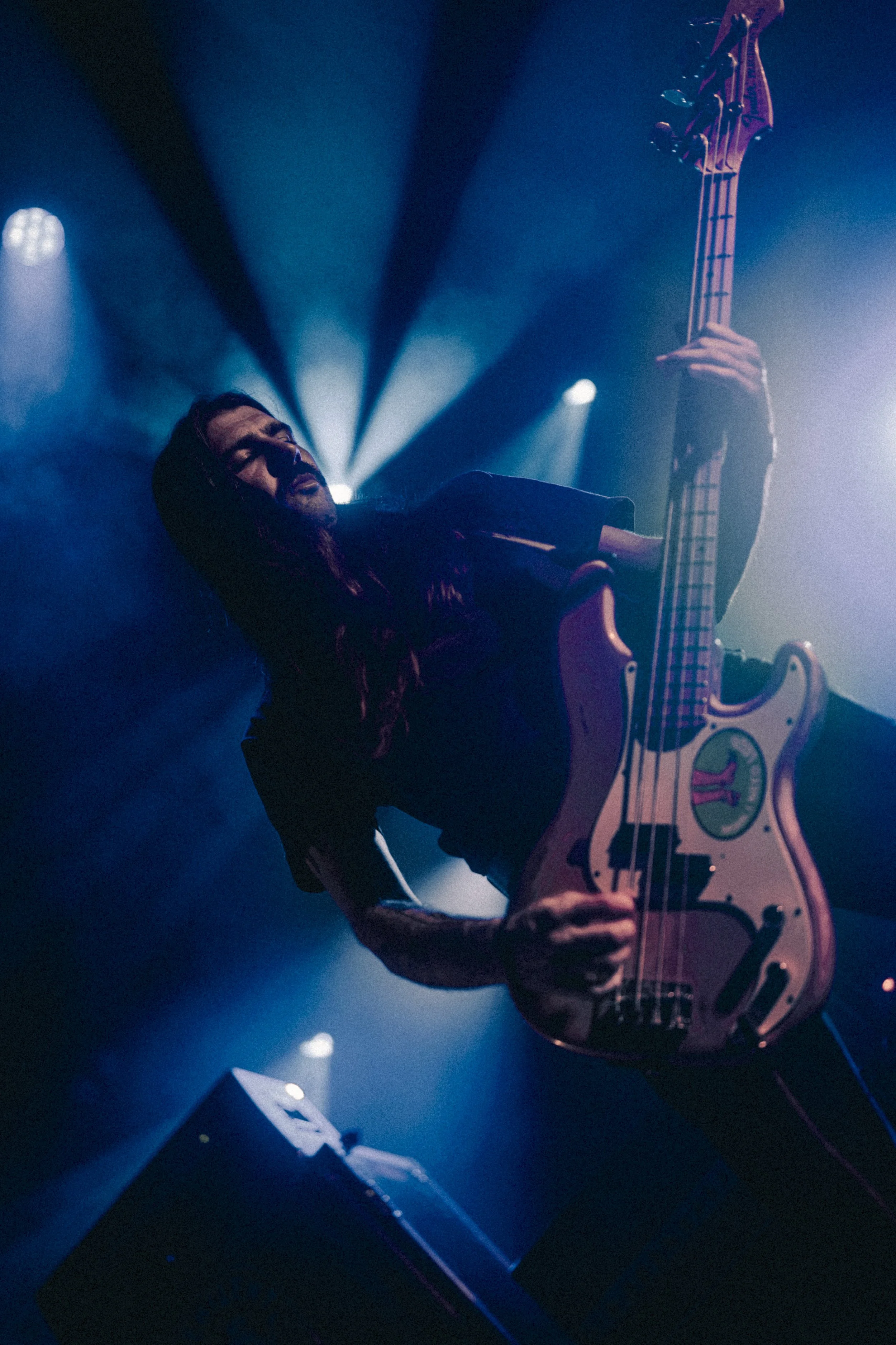 Musicien jouant de la guitare électrique en concert, éclairage bleu et violet, ambiance sombre et intense.