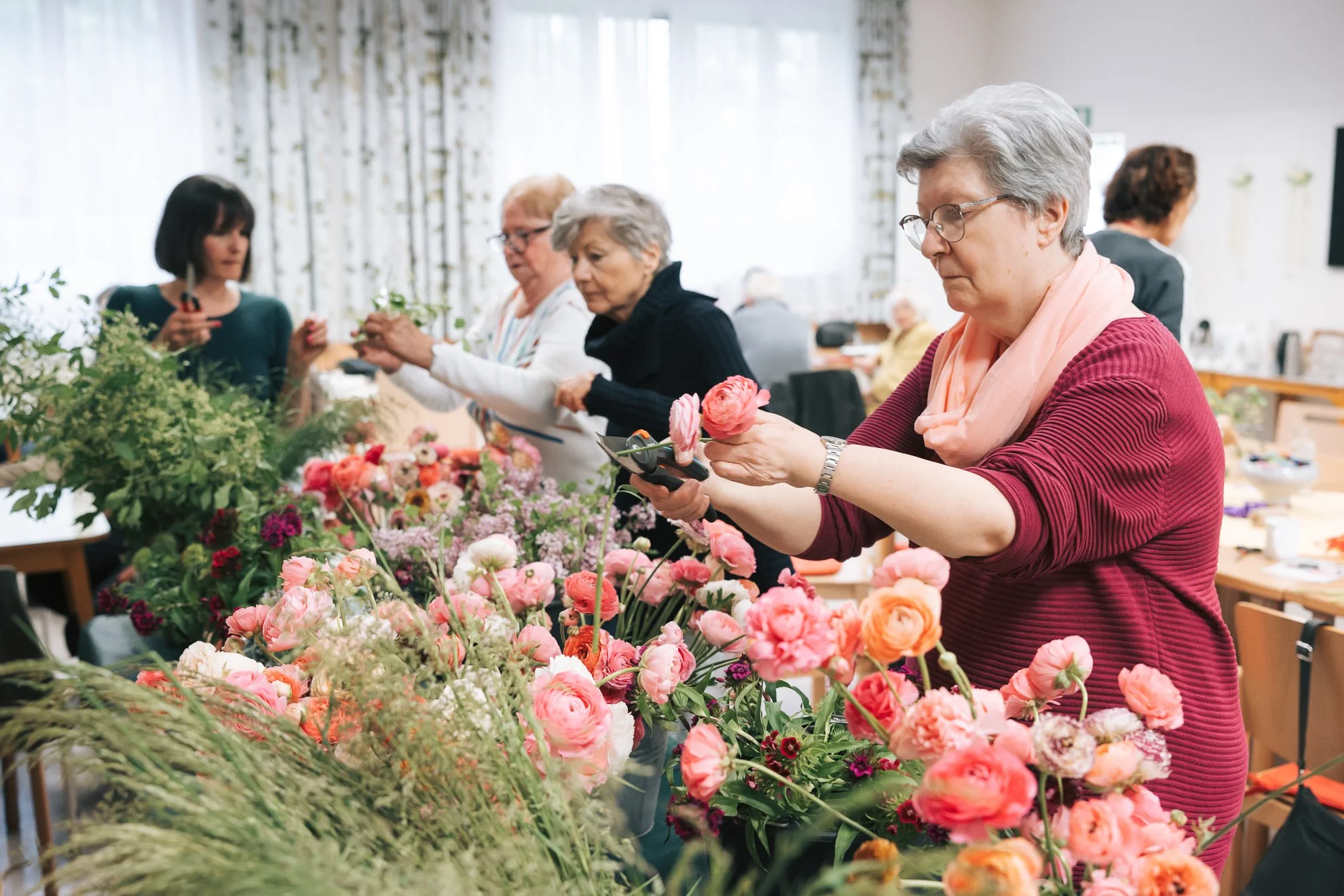 Frauen arrangieren Blumen in einem Raum mit heller Beleuchtung.