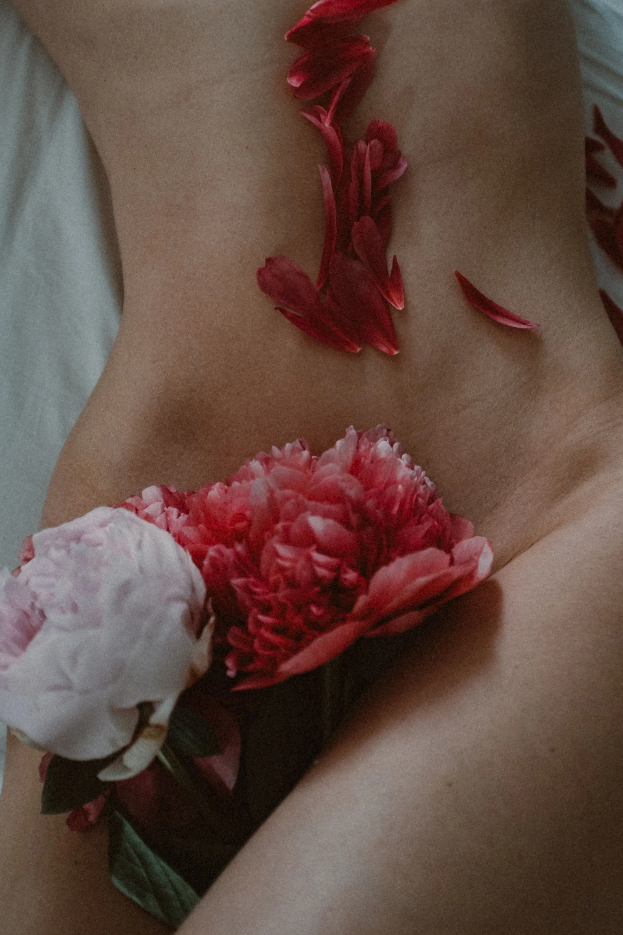 A semi naked woman lies with flowers placed on her body