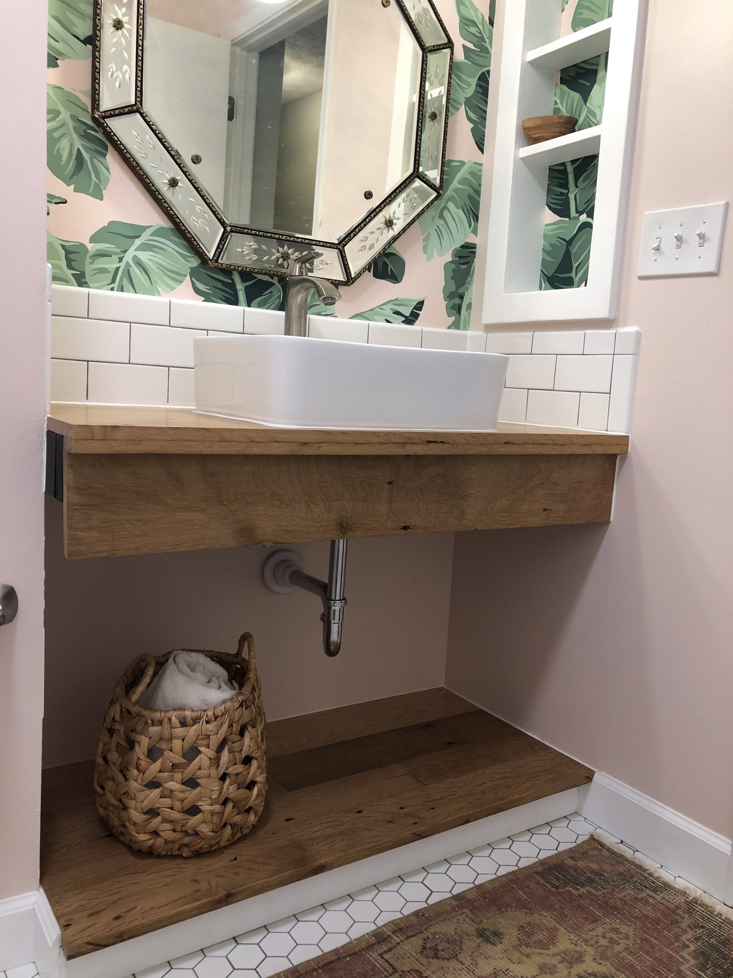 Custom vanity built from local reclaimed barn oak. Fixture Installation. Subway Tile Backsplash Installation. Wallpaper and Paint. Custom built in installed.